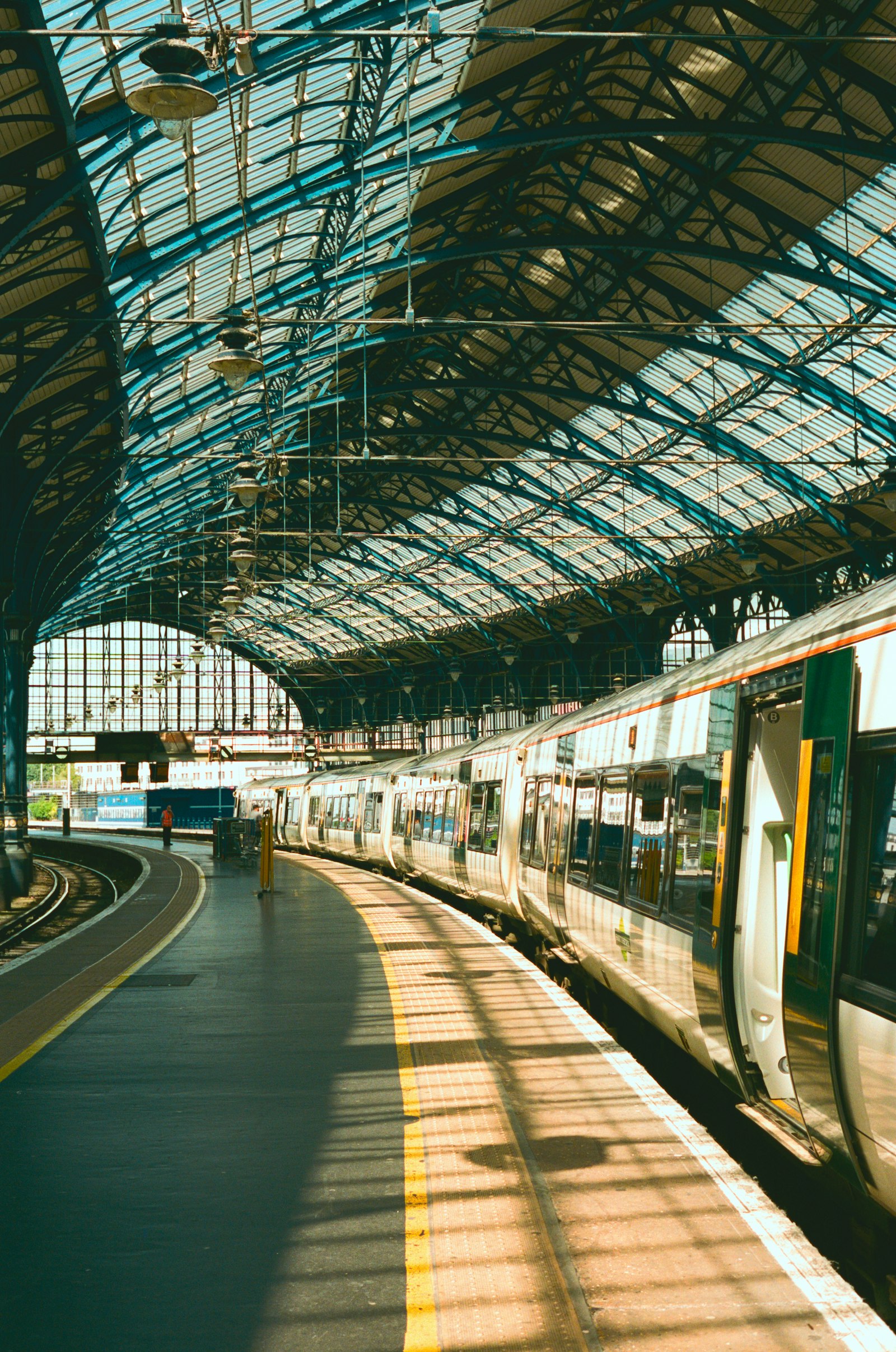 The curved glass and iron train shed at Brighton station with a train at the platform