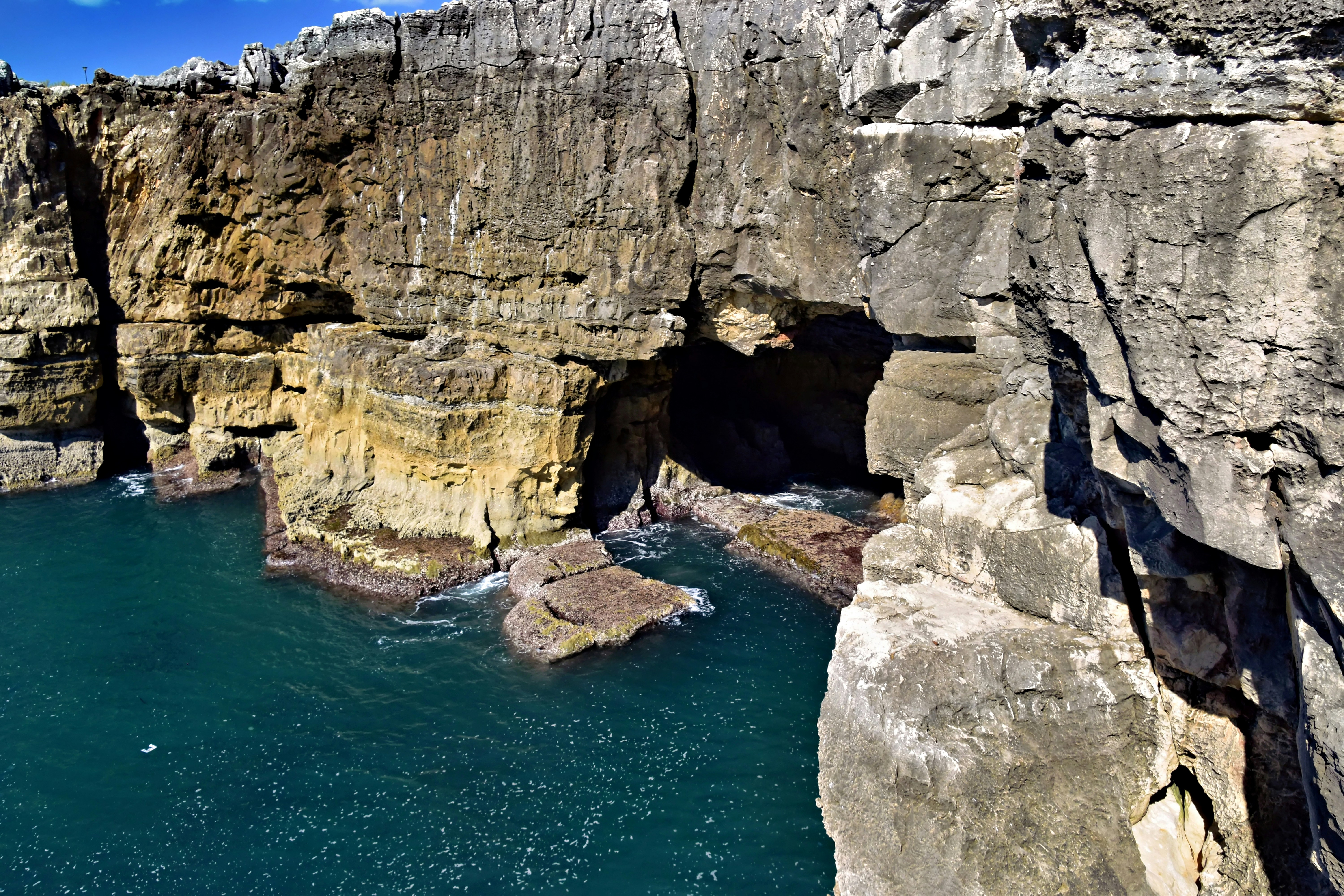 Rocky cliffs with a cave entrance by the ocean photo – Free Natural ...