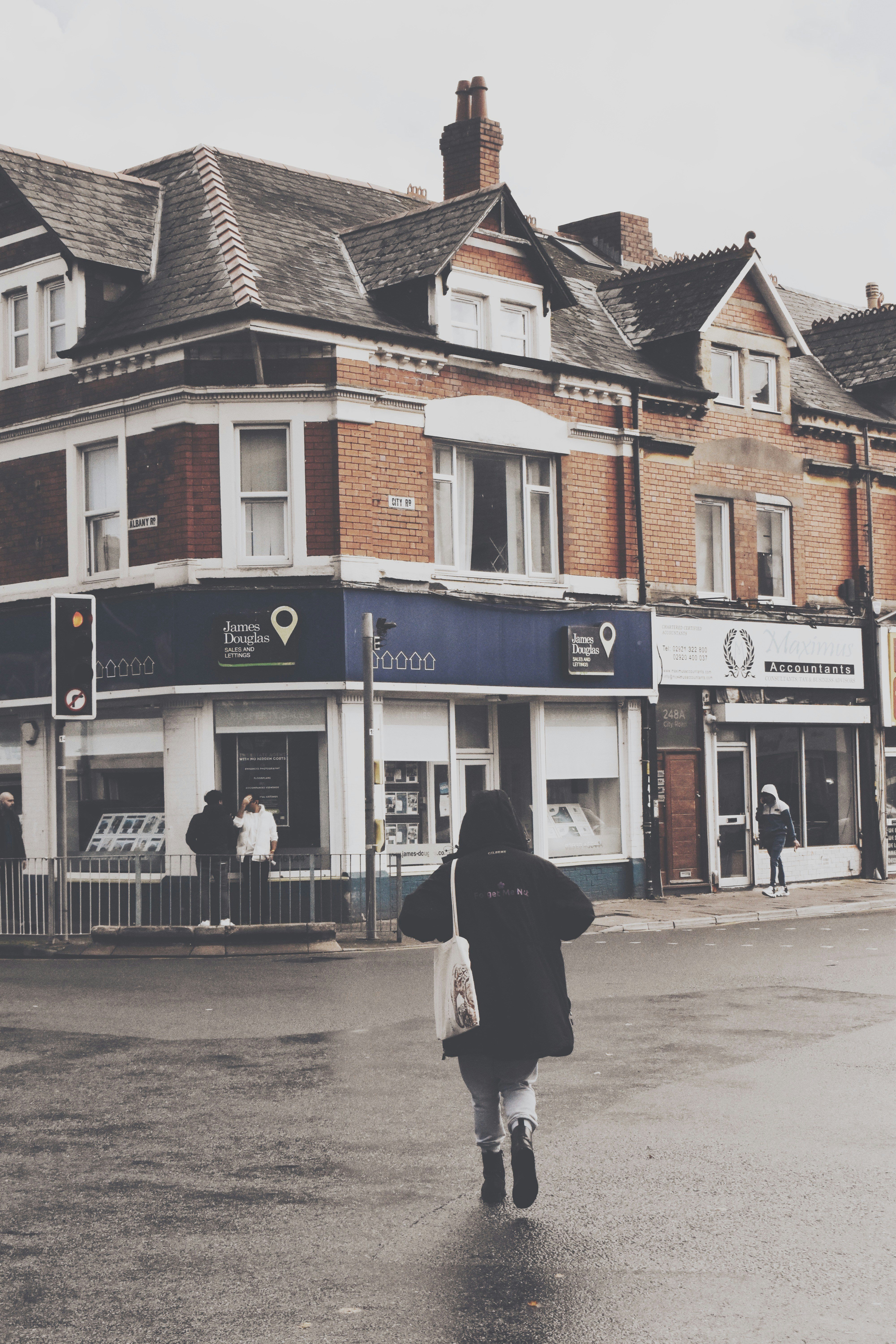 Une personne traversant une rue mouillée en direction des bâtiments.