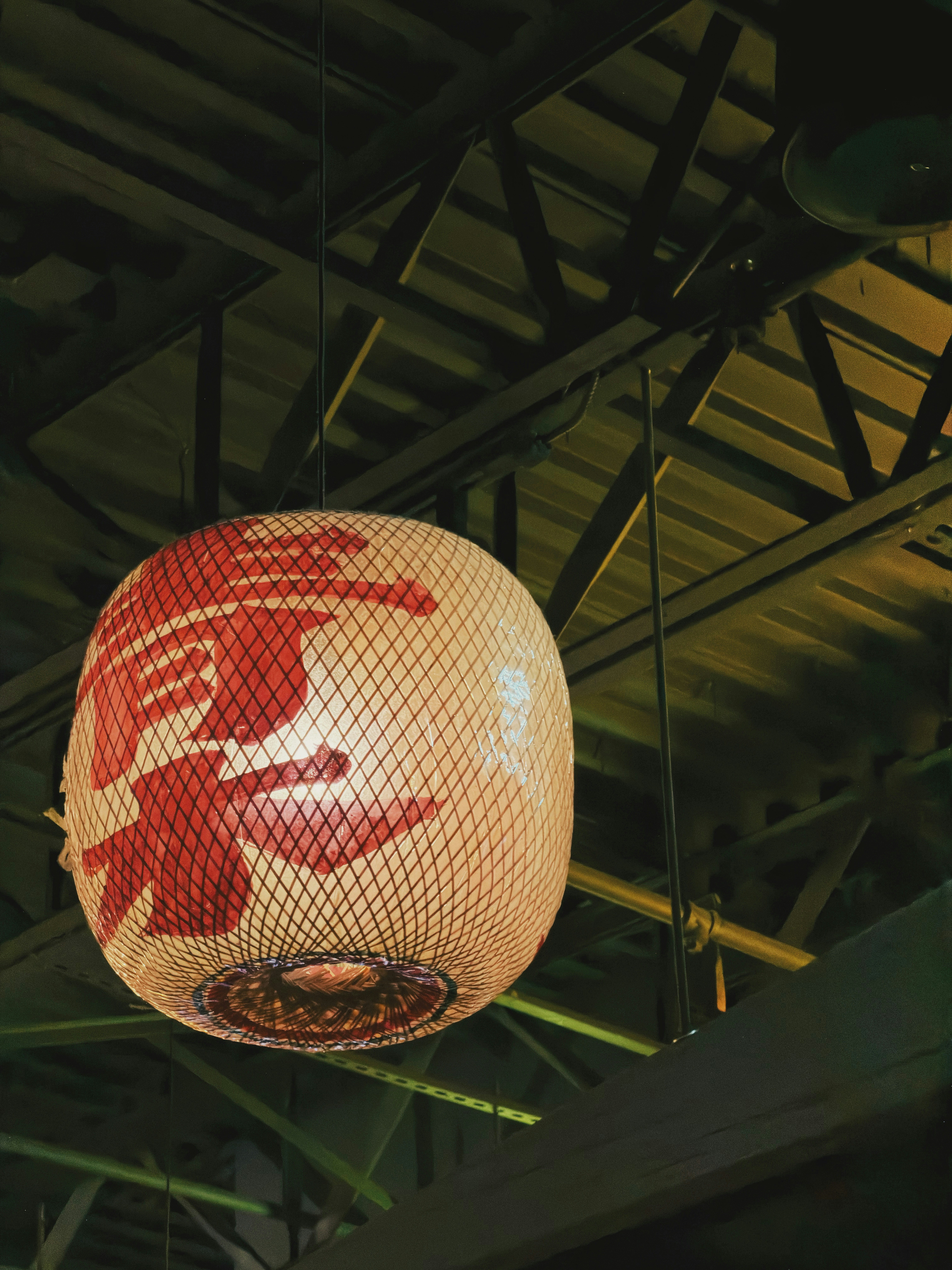 A round lantern with red japanese characters hangs indoors.