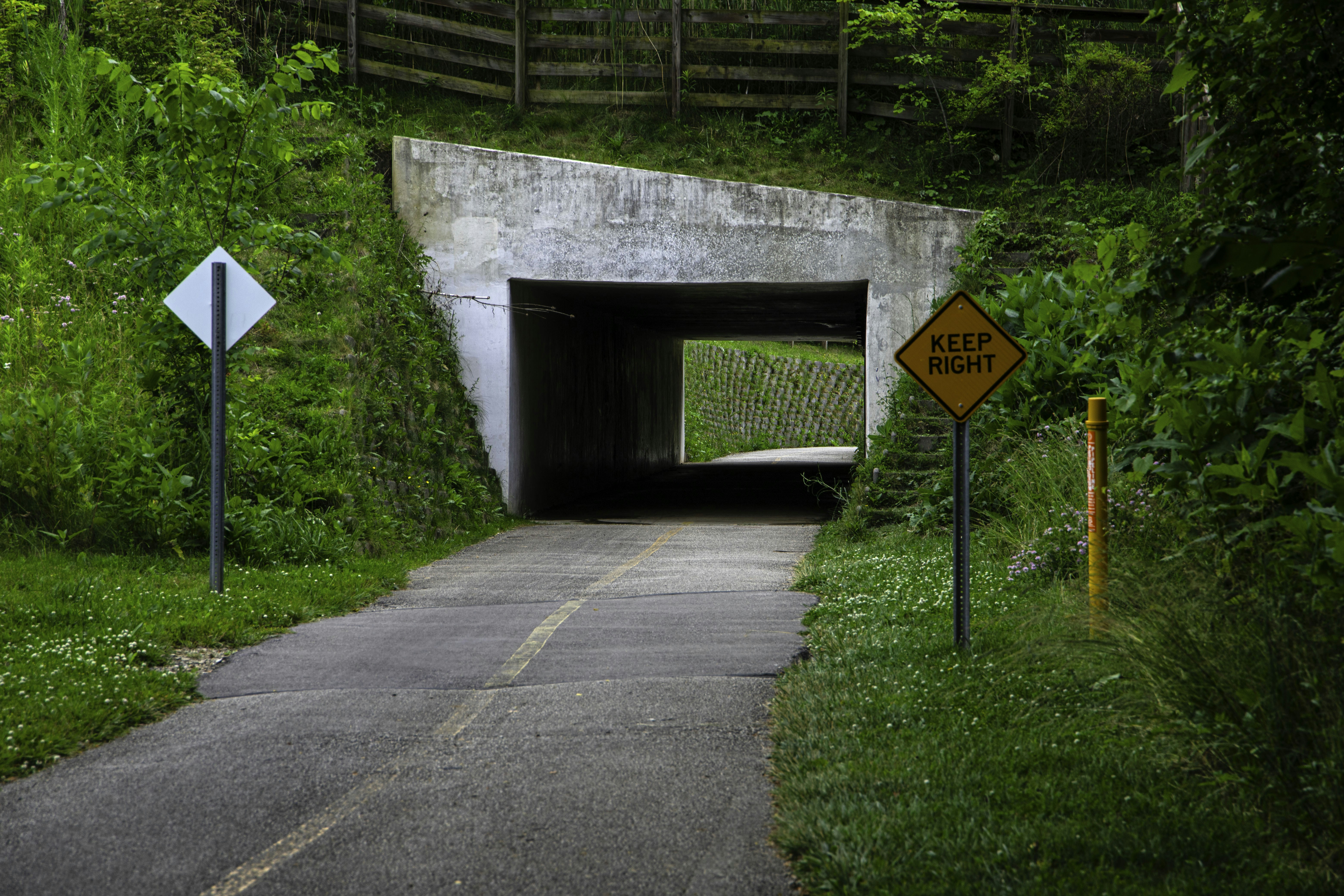Un chemin pavé mène à une entrée en béton par un tunnel.