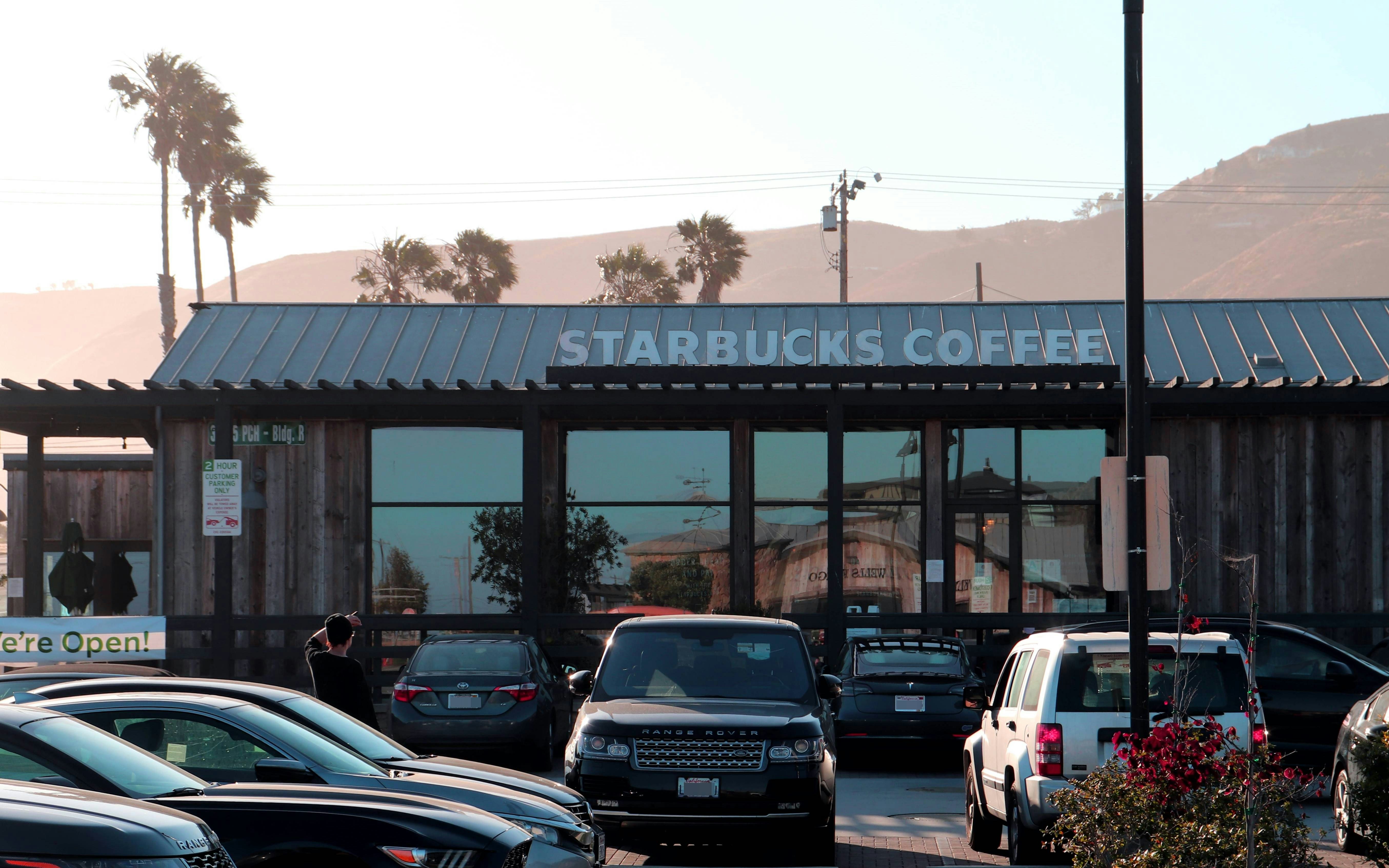 Starbucks coffee shop with cars in parking lot.