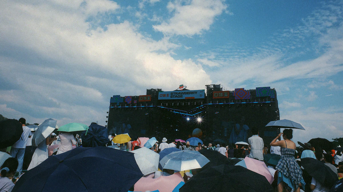 Crowd watches a concert on a stage under clouds