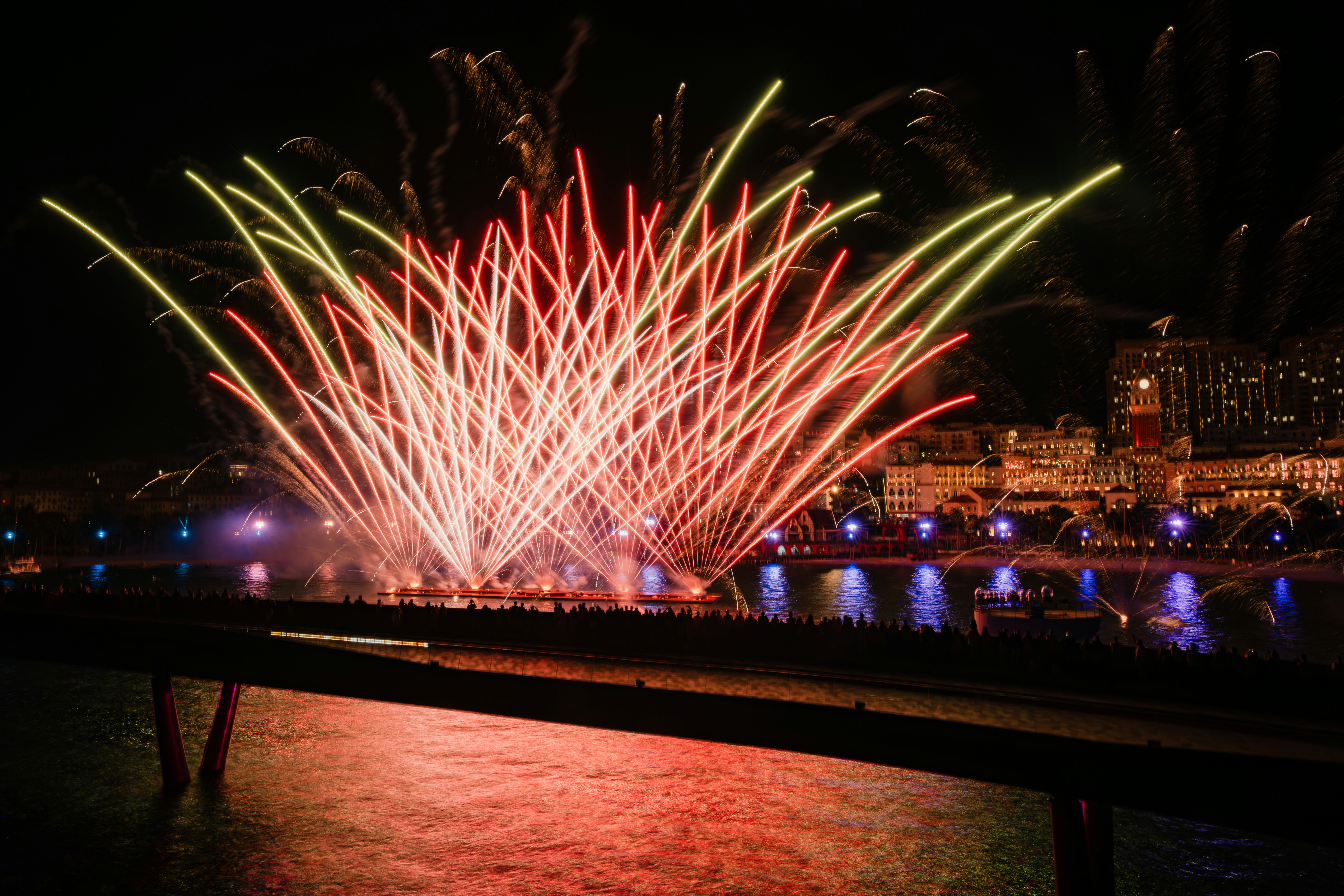 Fireworks explode over a city skyline at night.