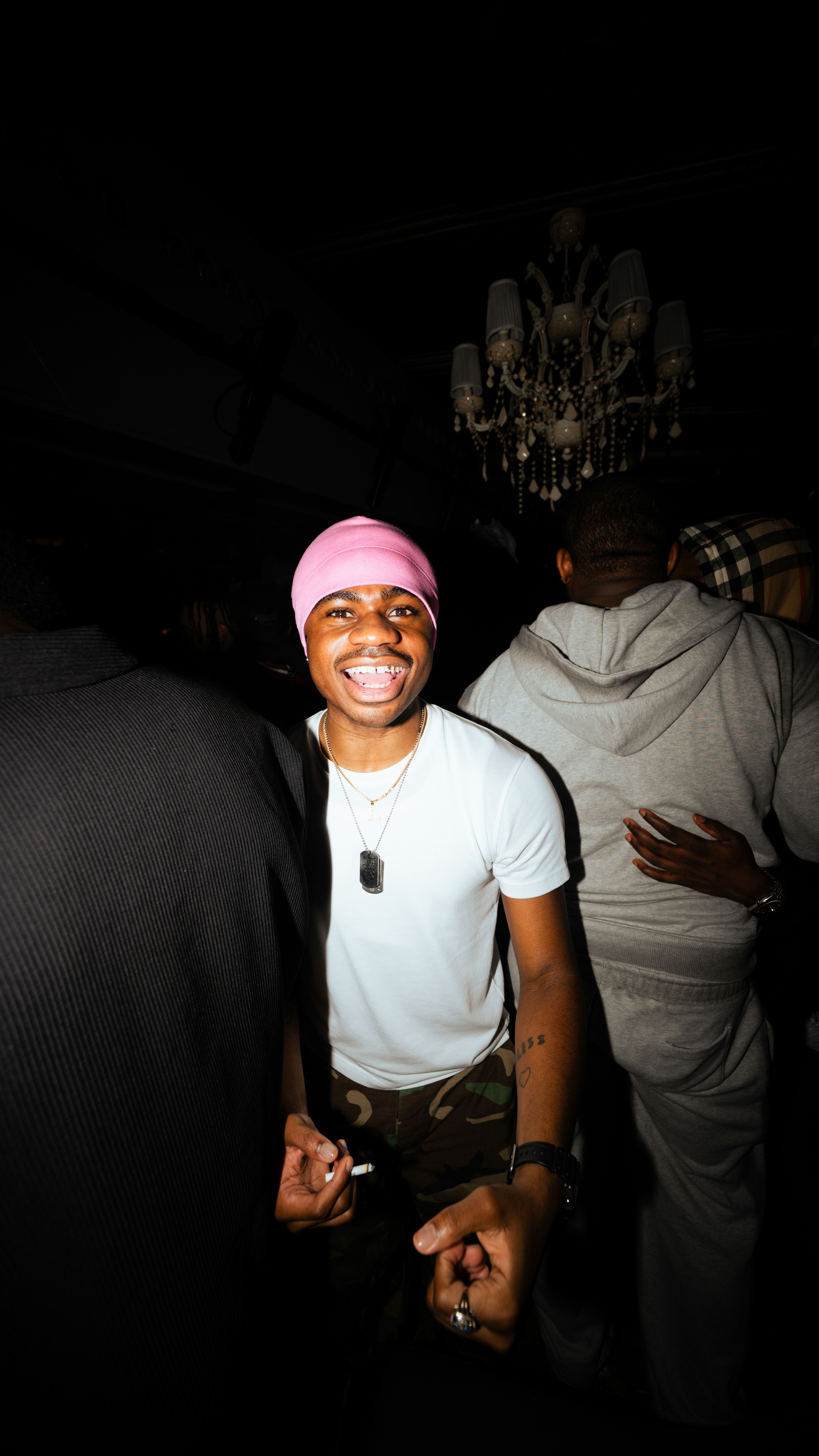 Giovane con il berretto rosa che sorride alla telecamera.