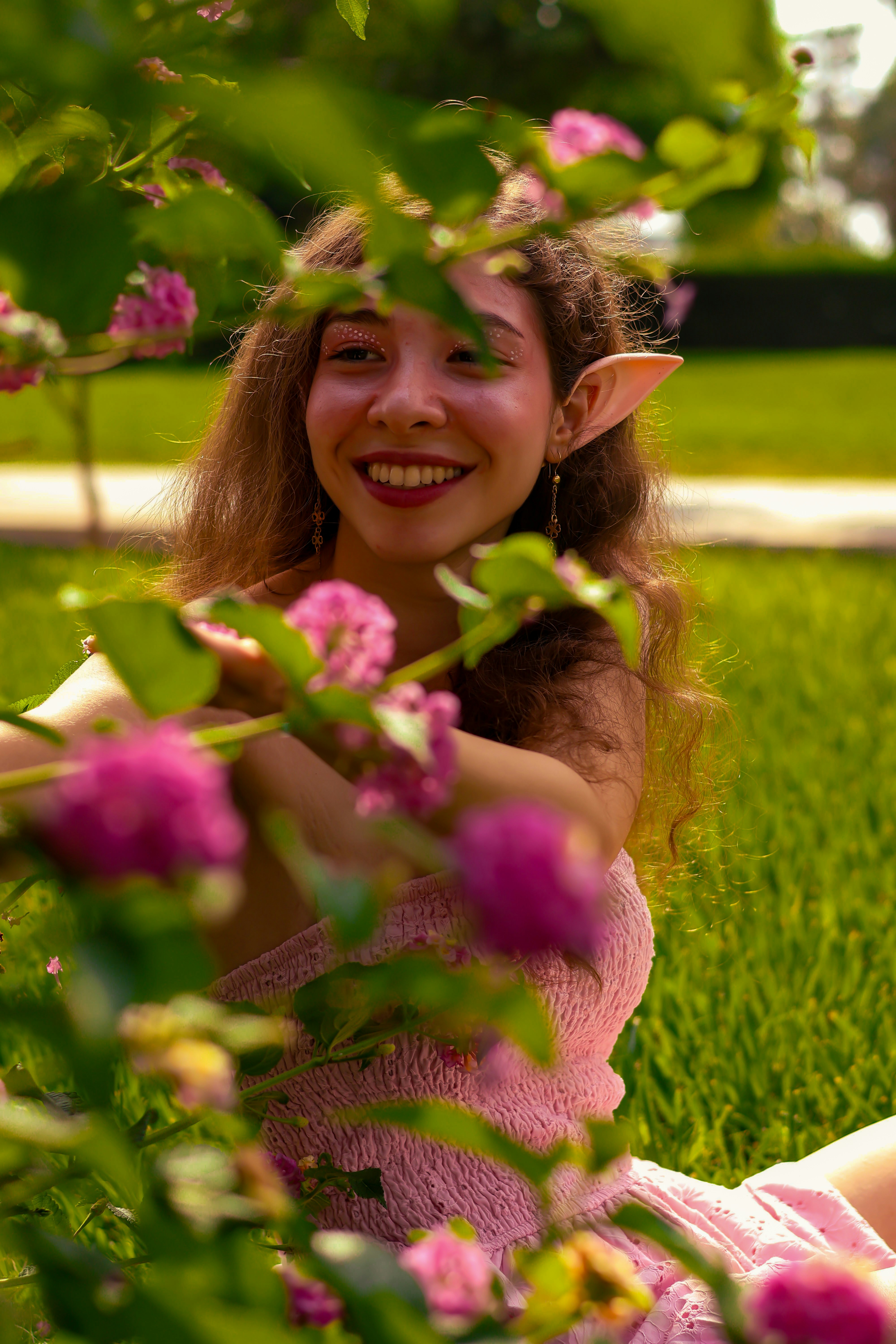 Joven con orejas de elfo entre flores rosas