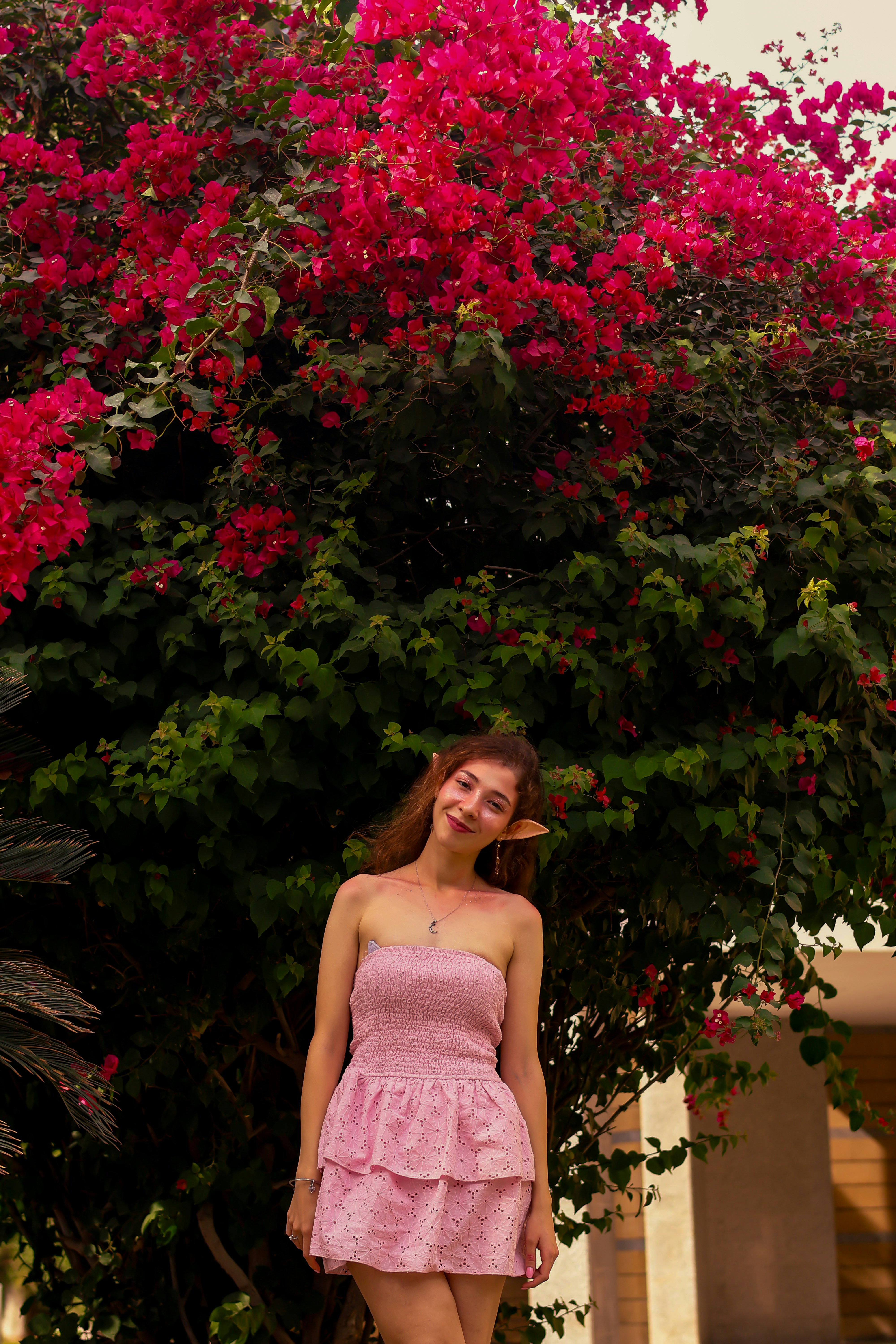 Mujer con vestido rosa bajo flores rosas vibrantes