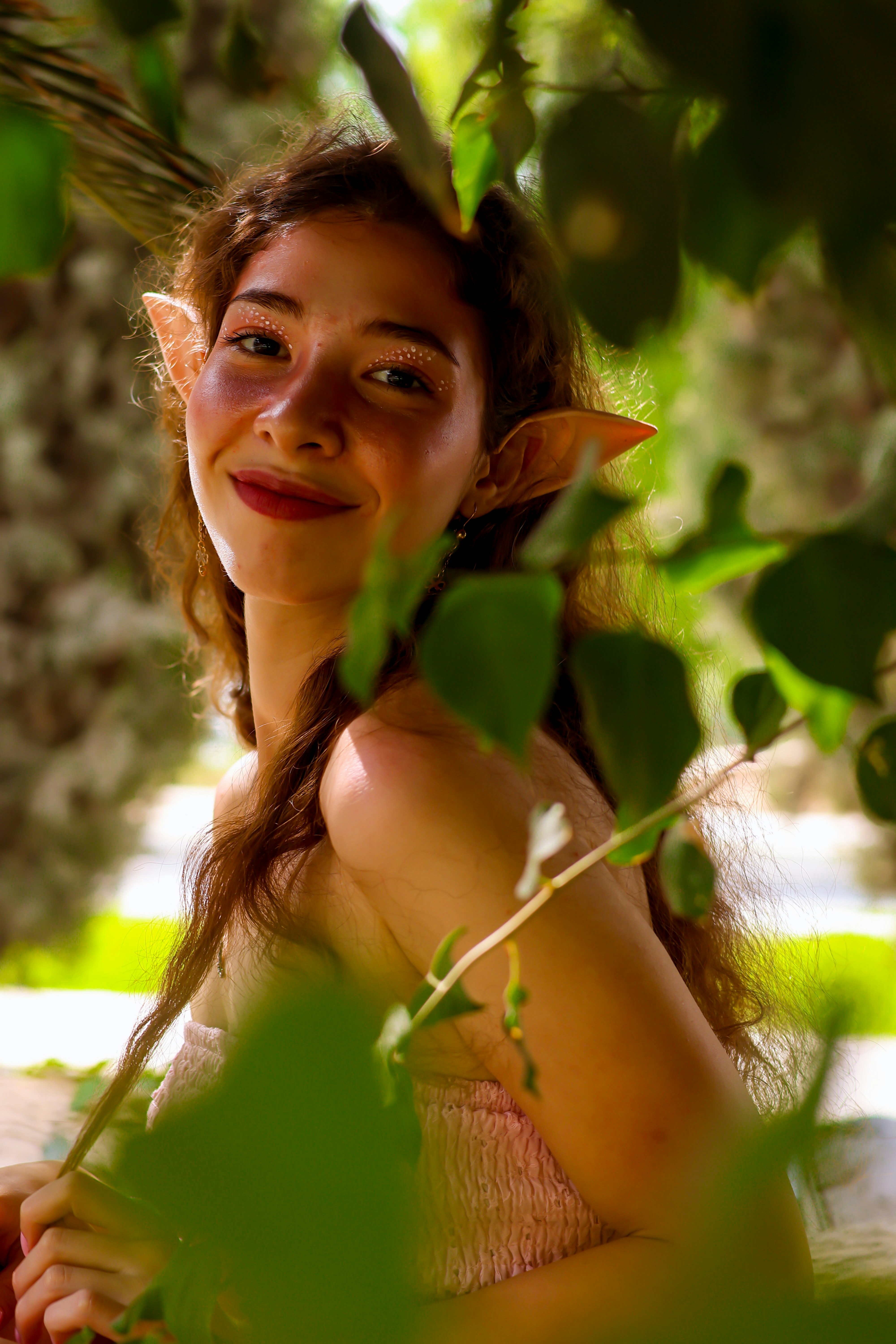 Young woman with elf ears peeking through leaves
