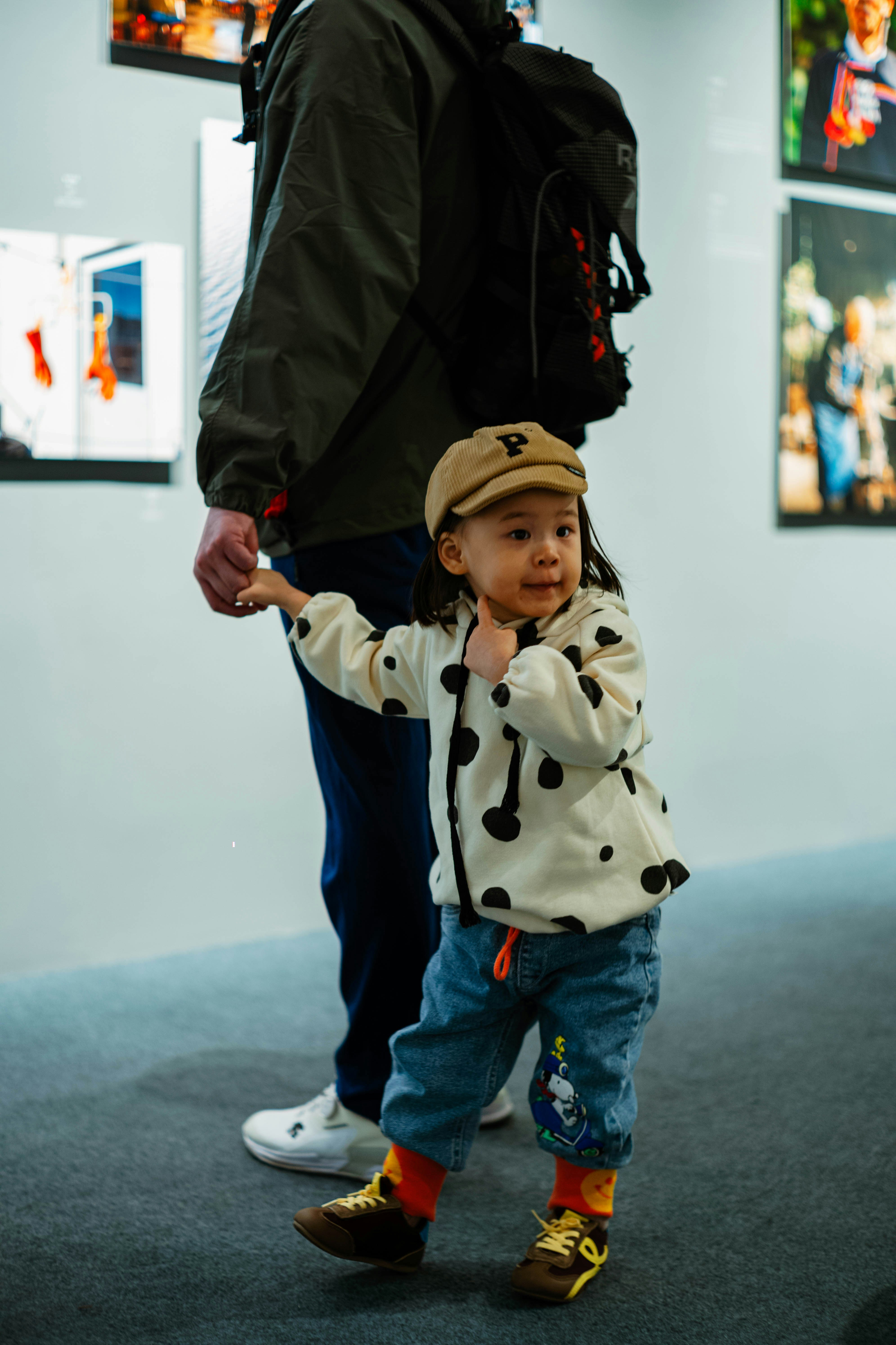 A child holds an adult's hand at an exhibition.