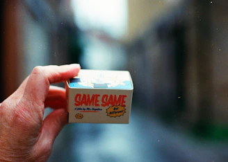 Hand holding a small box with text 'same same'
