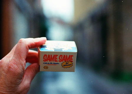 Hand holding a small box with text 'same same'