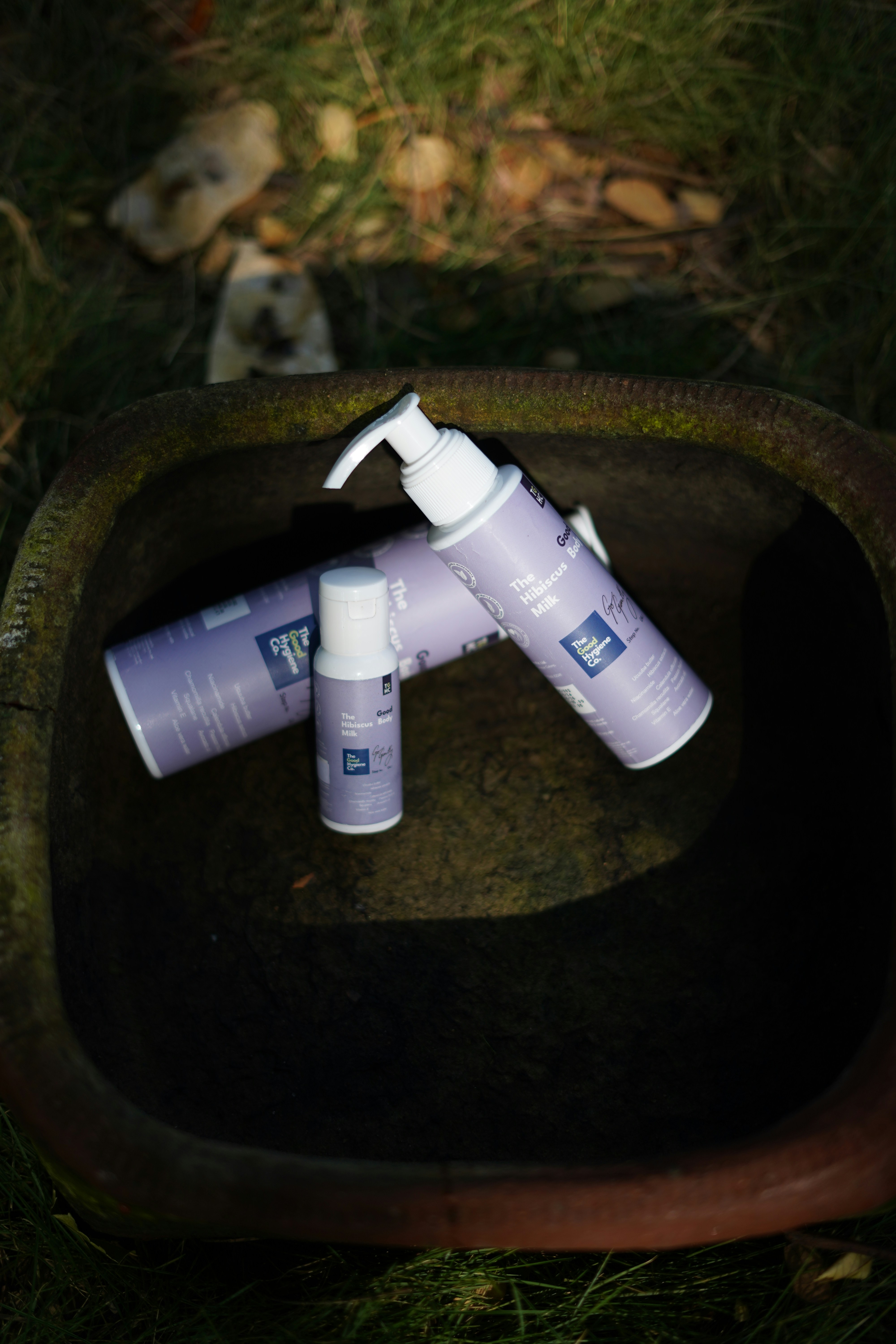 Three purple bottles with white labels in a rustic bowl.