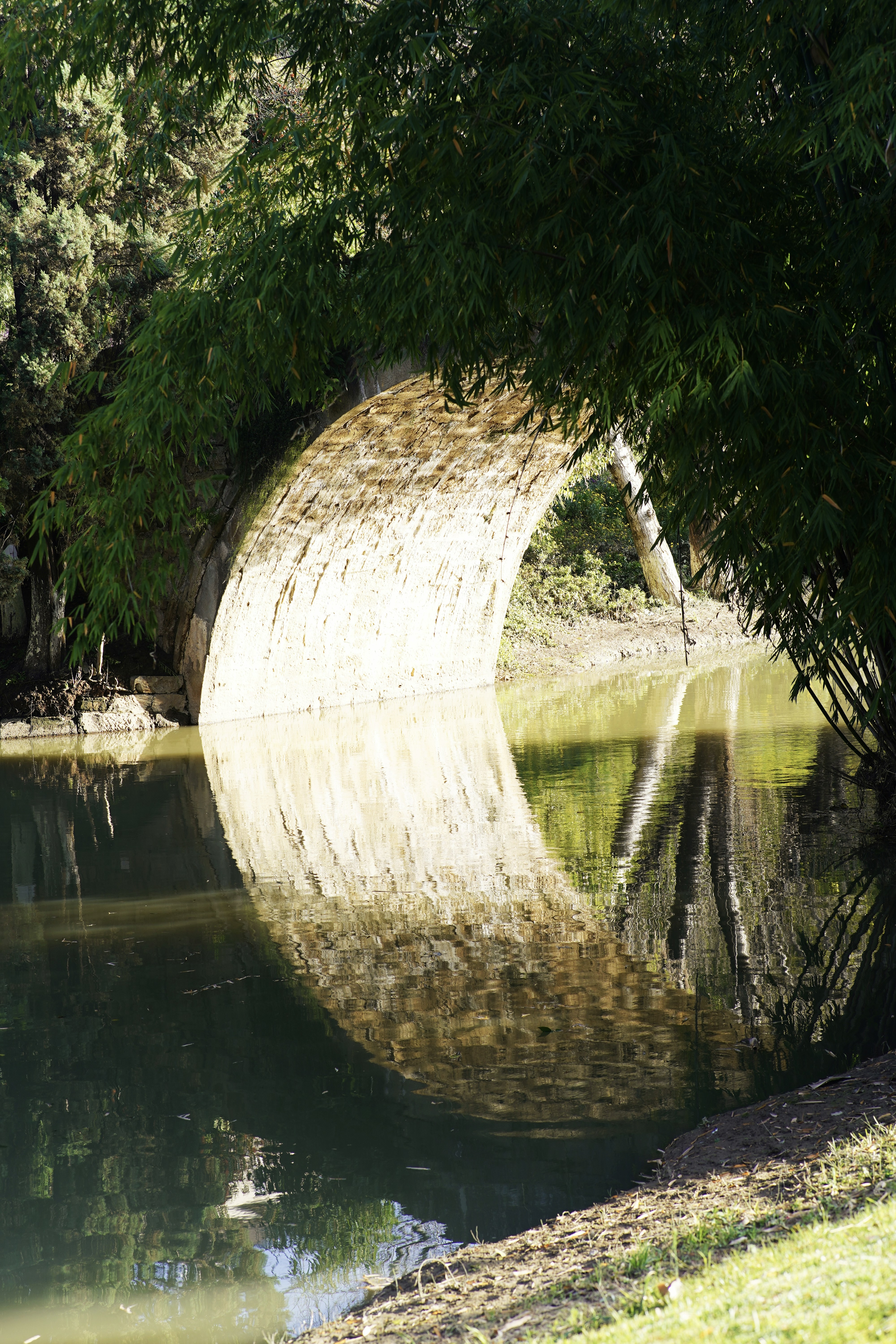 Steinbogenbrücke spiegelt sich im ruhigen Wasser wider