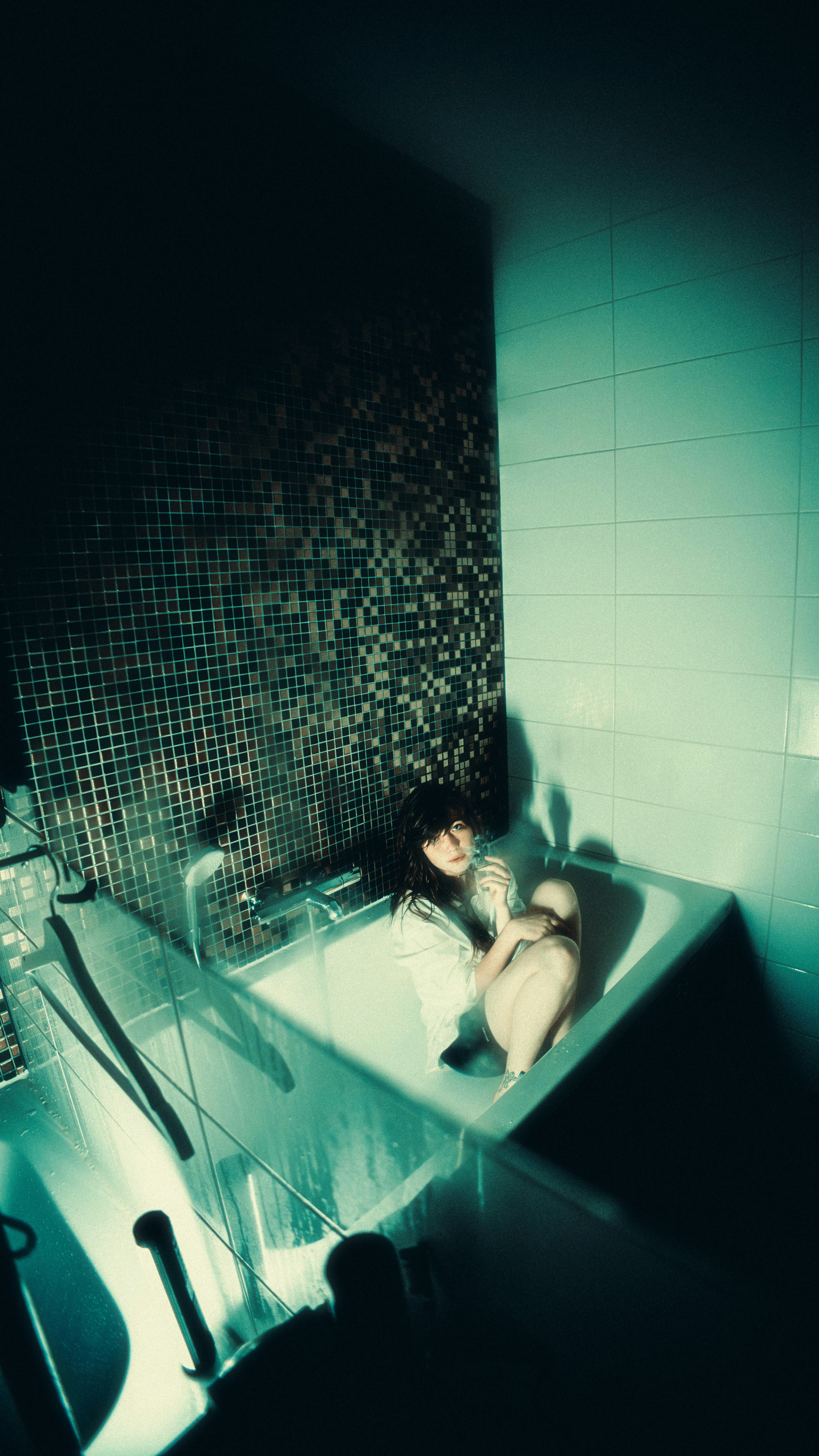 Woman sitting in a bathtub with mosaic tiles
