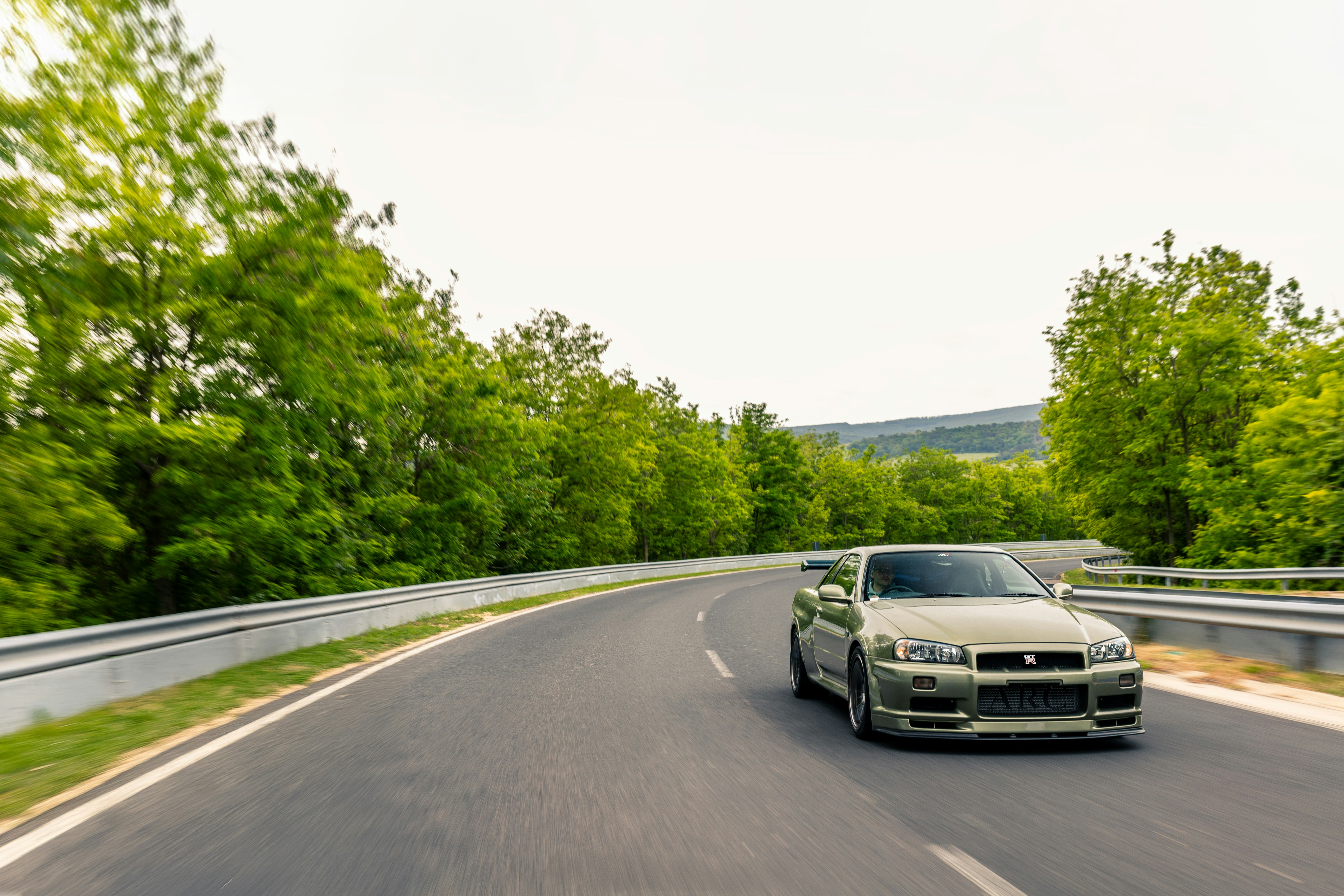 A silver sports car drives on a winding road.