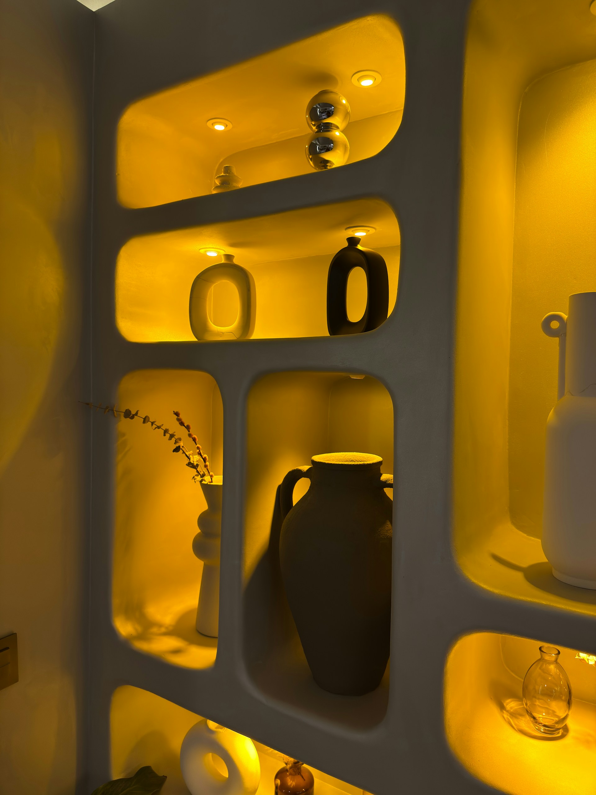 Vases displayed in illuminated yellow wall niches