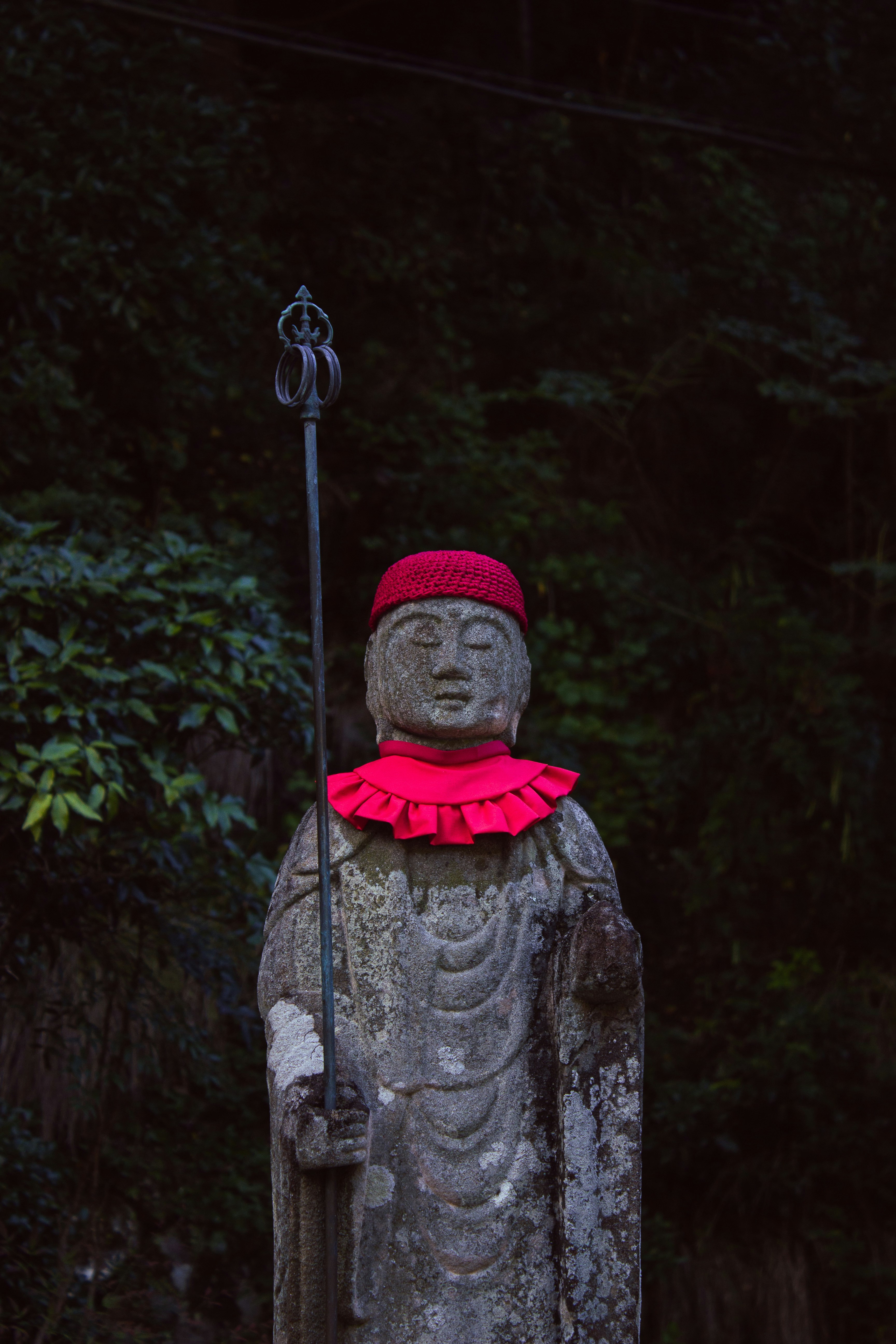 Stone statue with red hat and staff