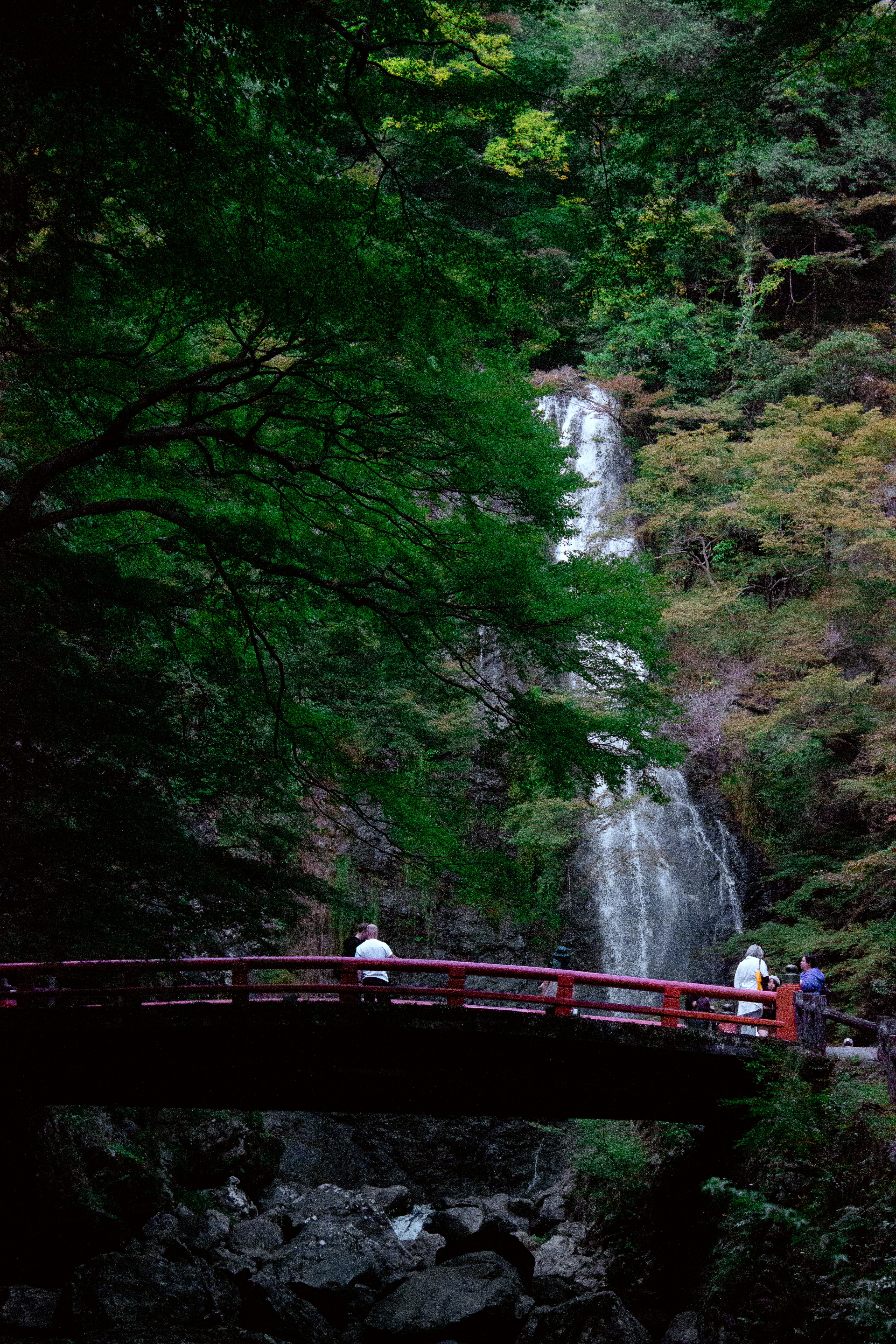 People on a red bridge near a waterfall