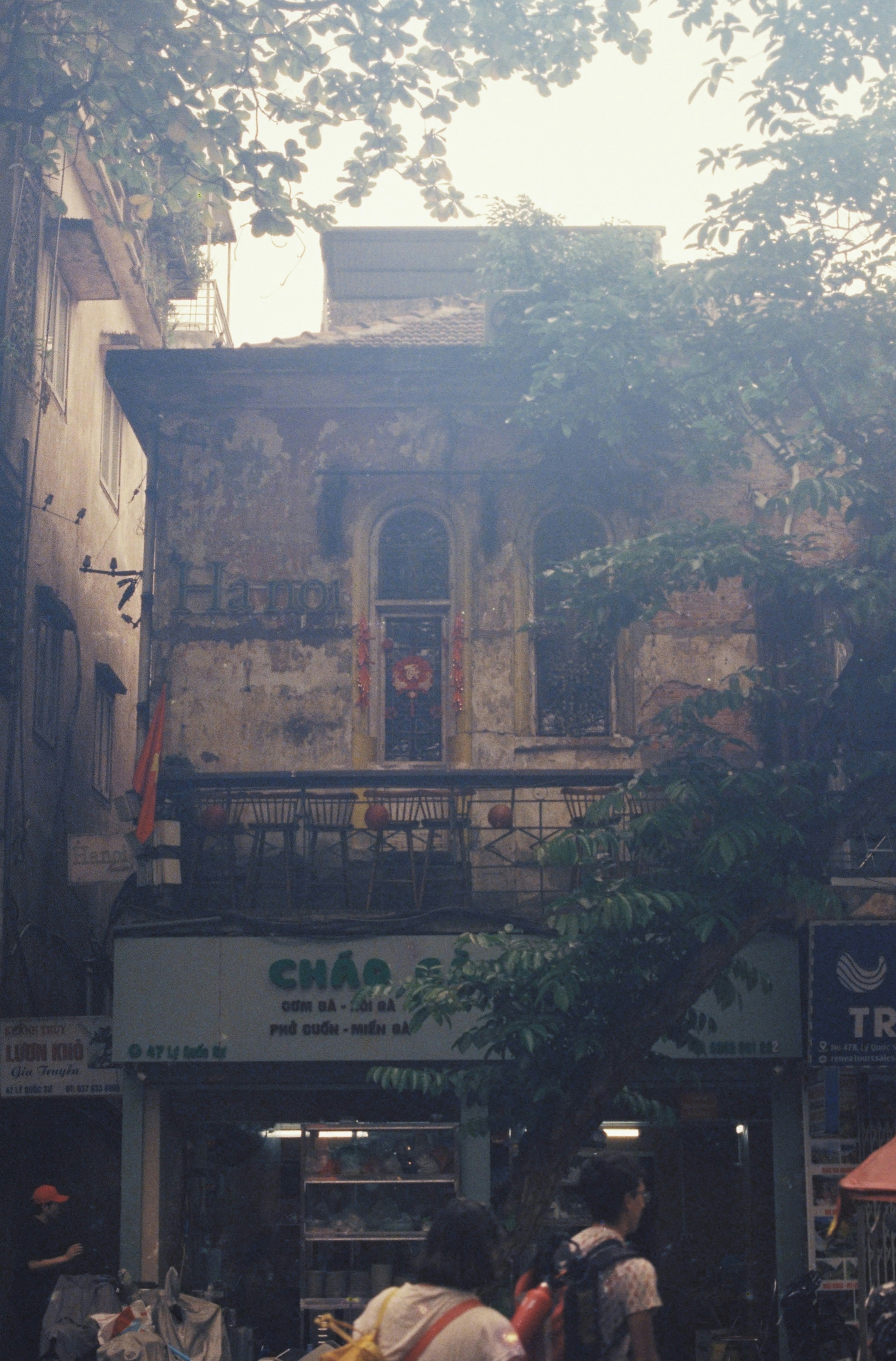 Old building facade with trees and street activity.