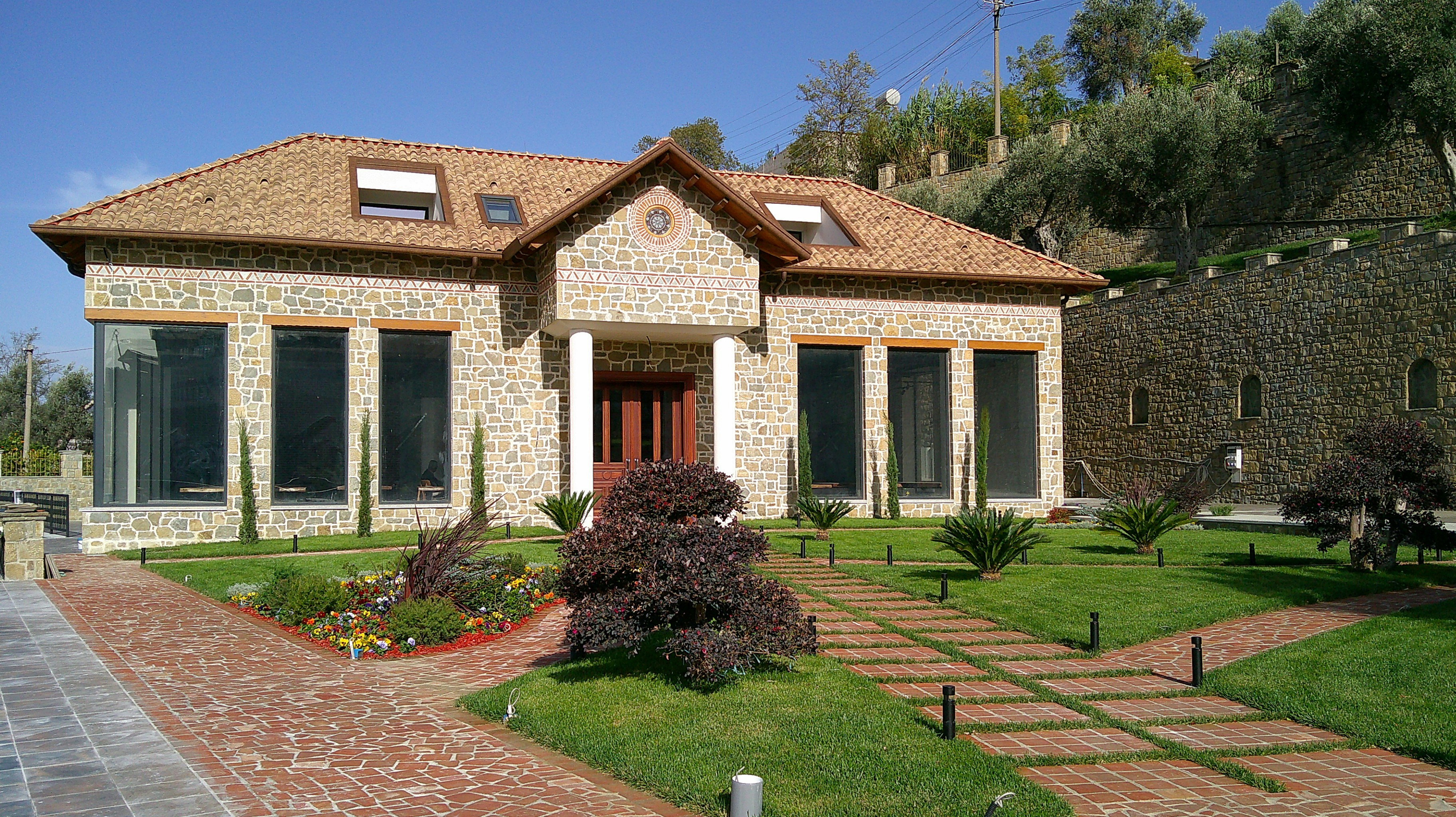 Stone house with large windows and manicured lawn