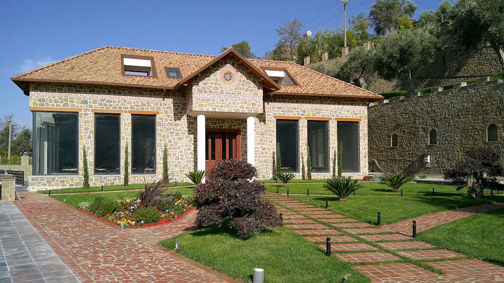 Stone house with a brick walkway through a freshly sodded lawn