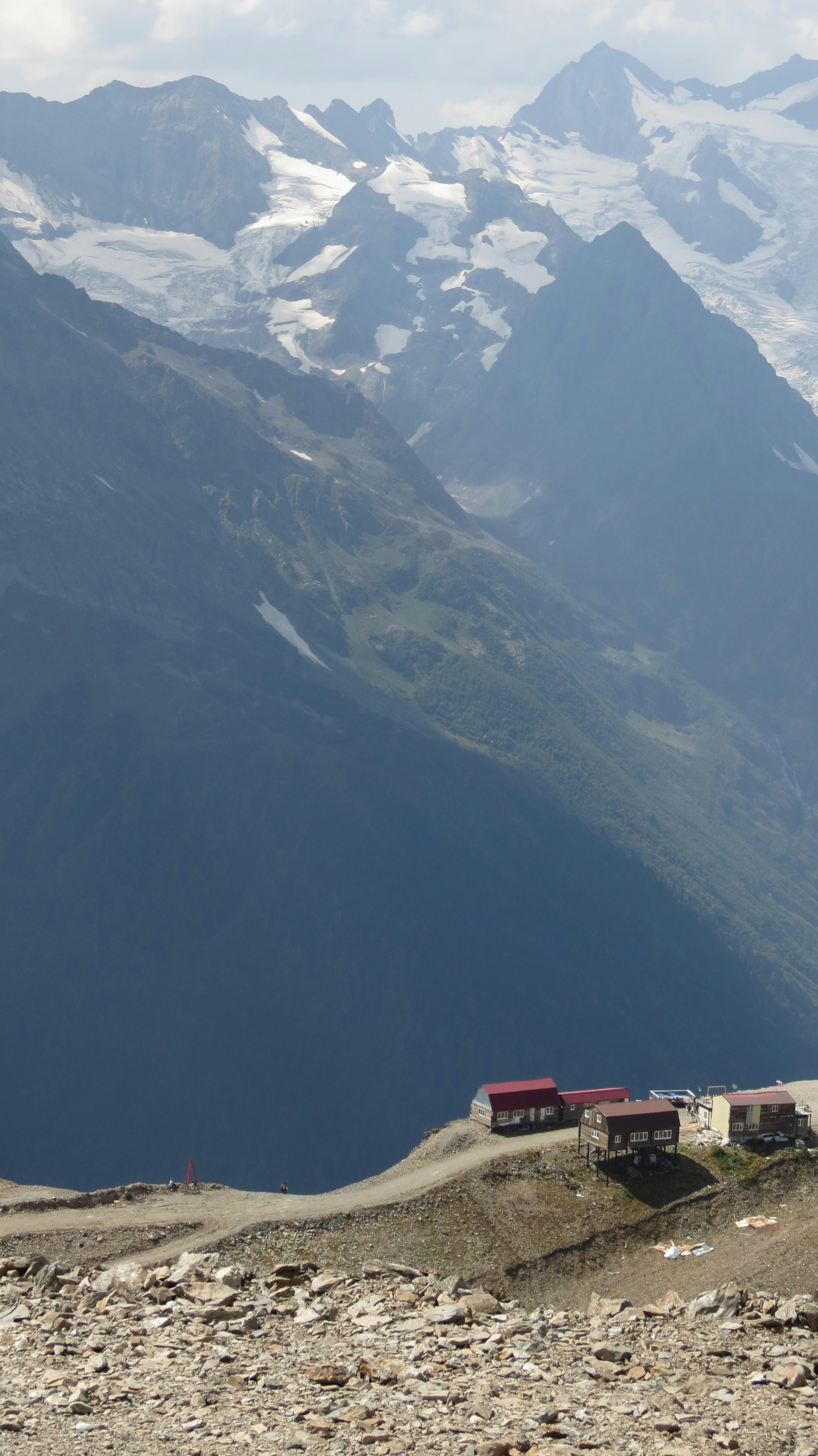 Buildings on a mountain ridge with snowy peaks behind.