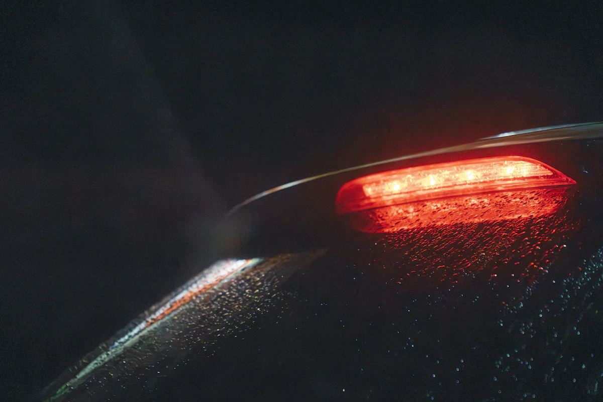 A brake light glowing on a wet car at night