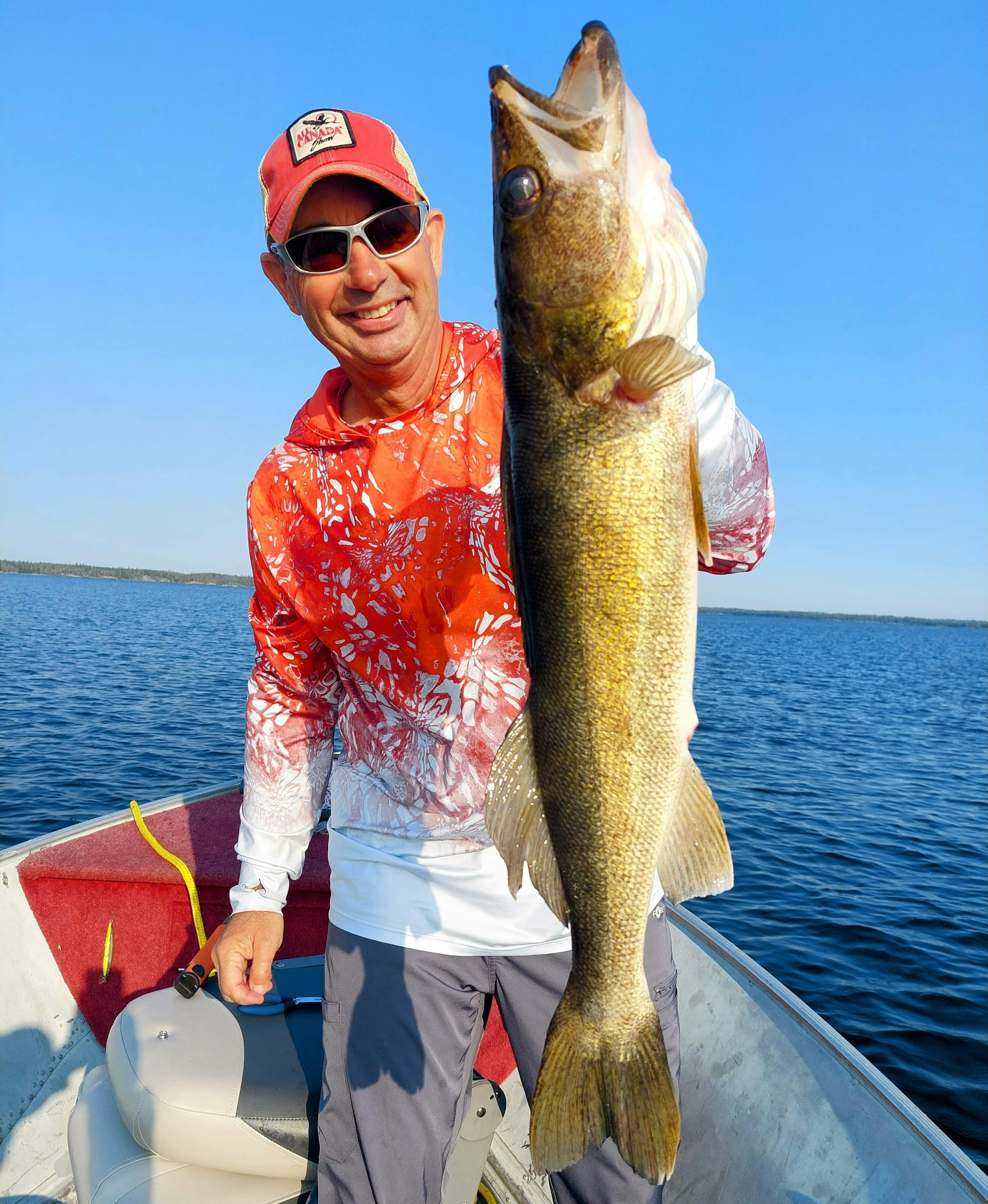 Man holding a large walleye fish from a boat.