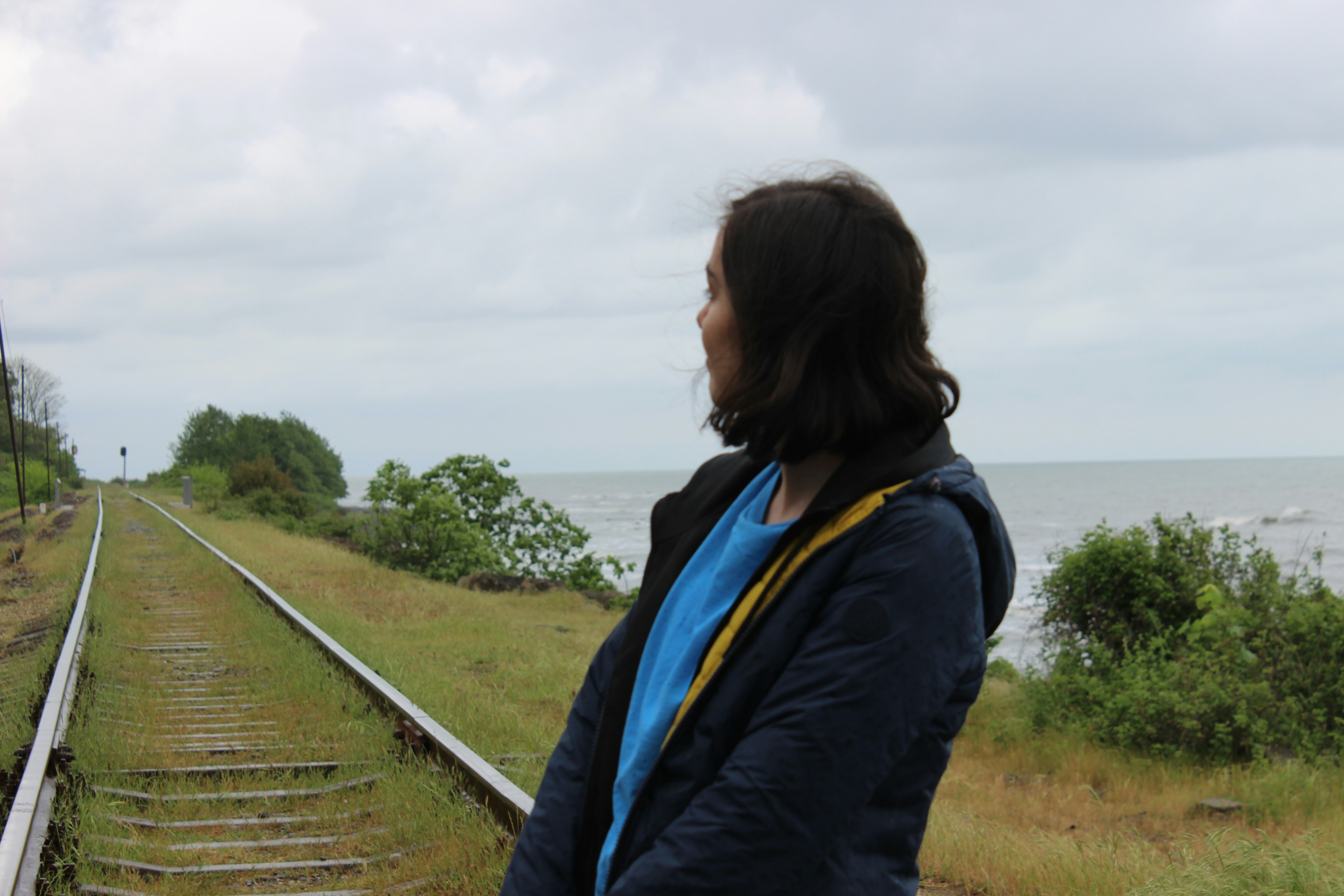 Woman looking out at the ocean near train tracks