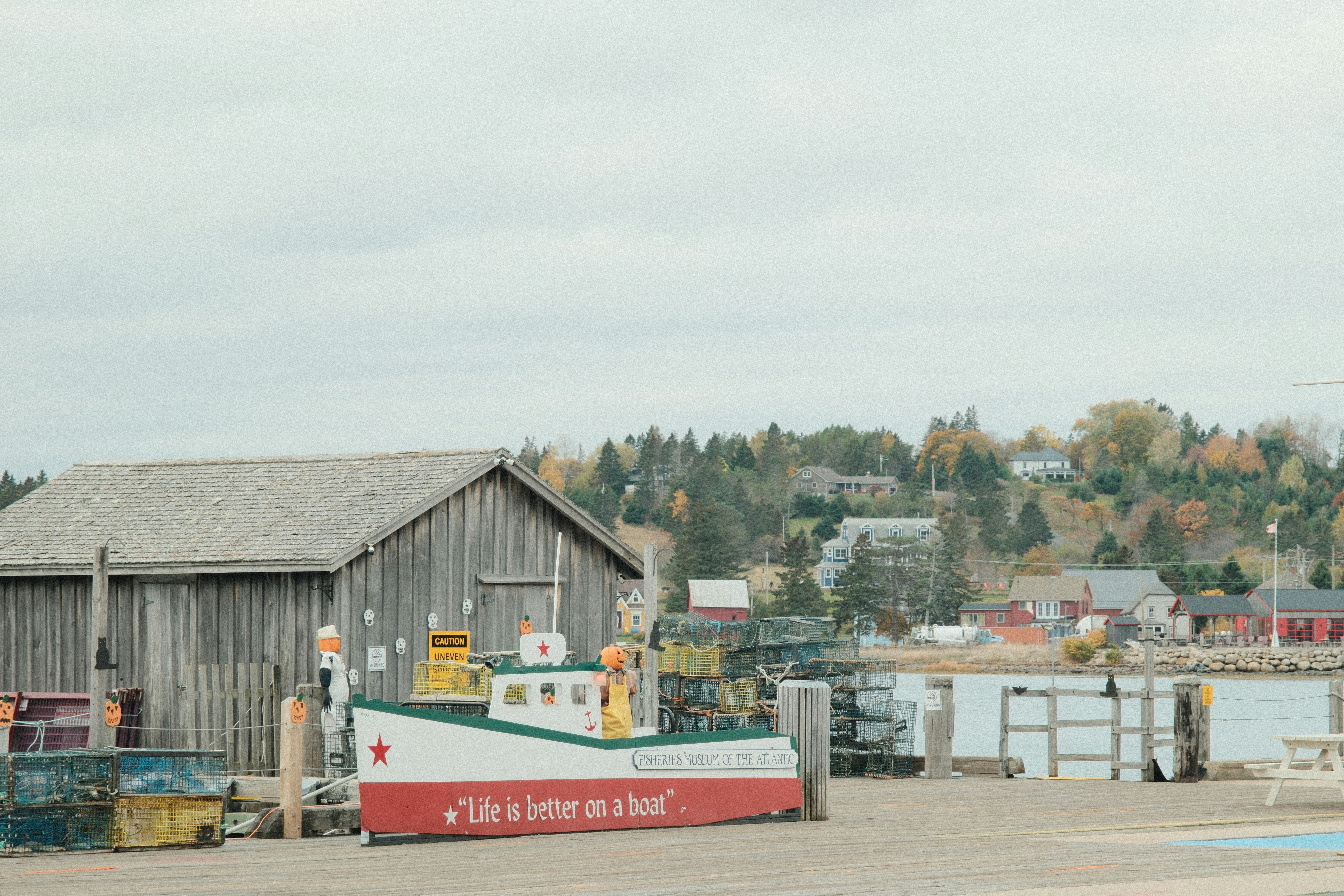 A small boat decoration sits by a wooden building.