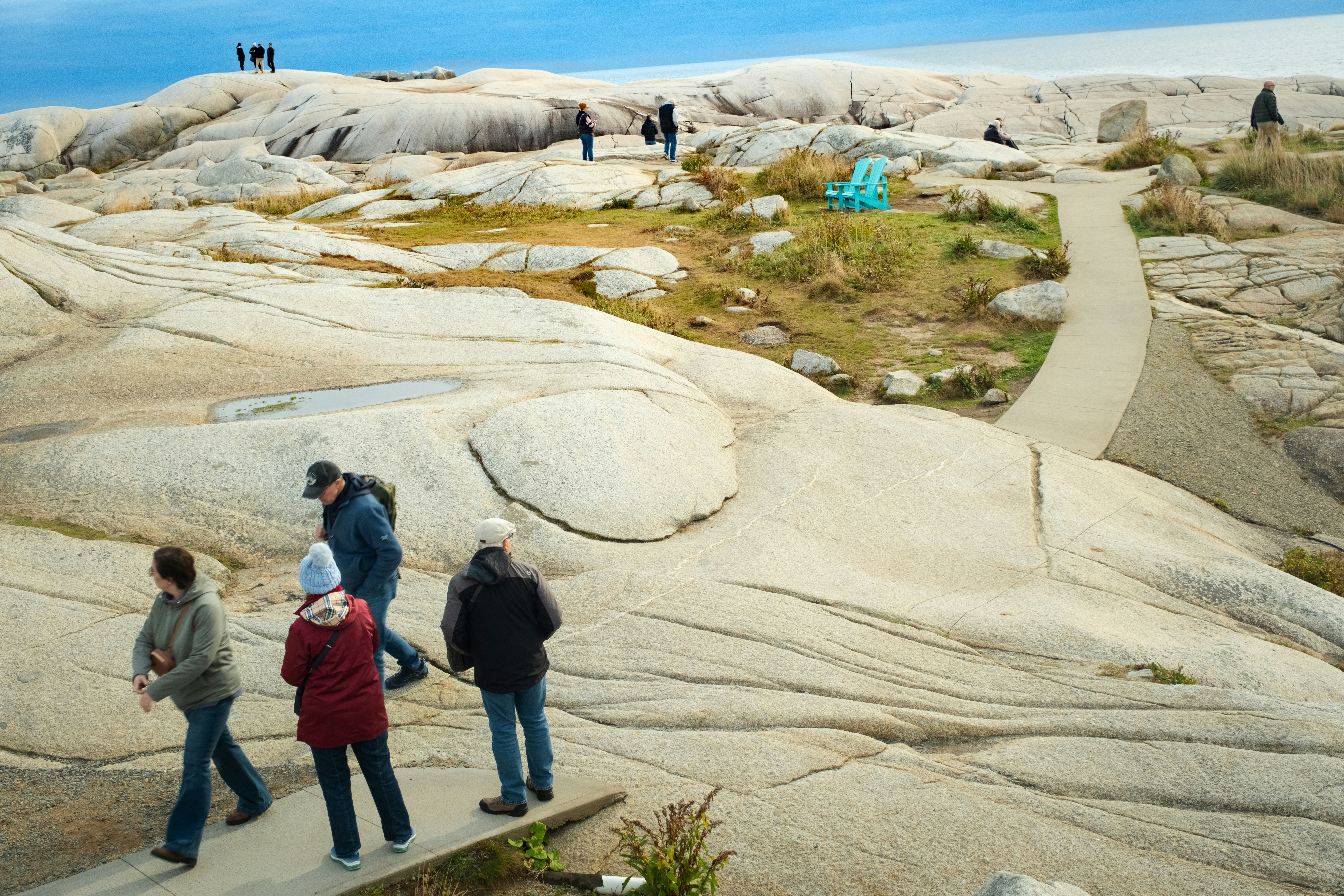 People walk on a rocky coastline with a path.