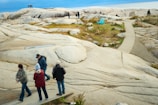 People walk on a rocky coastline with a path.