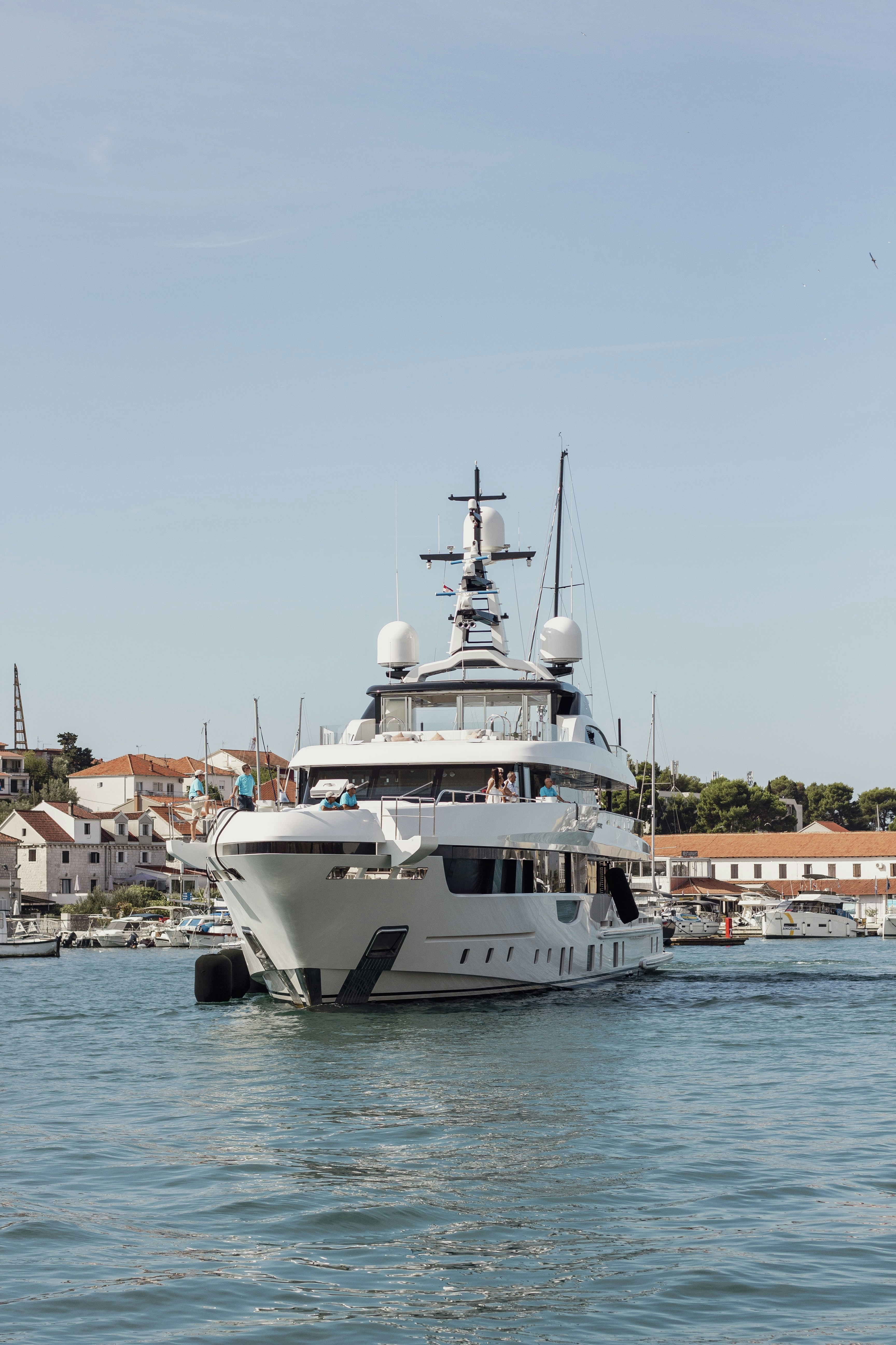 큰 흰색 요트가 건물 근처의 푸른 바다를 항해하고 있다.