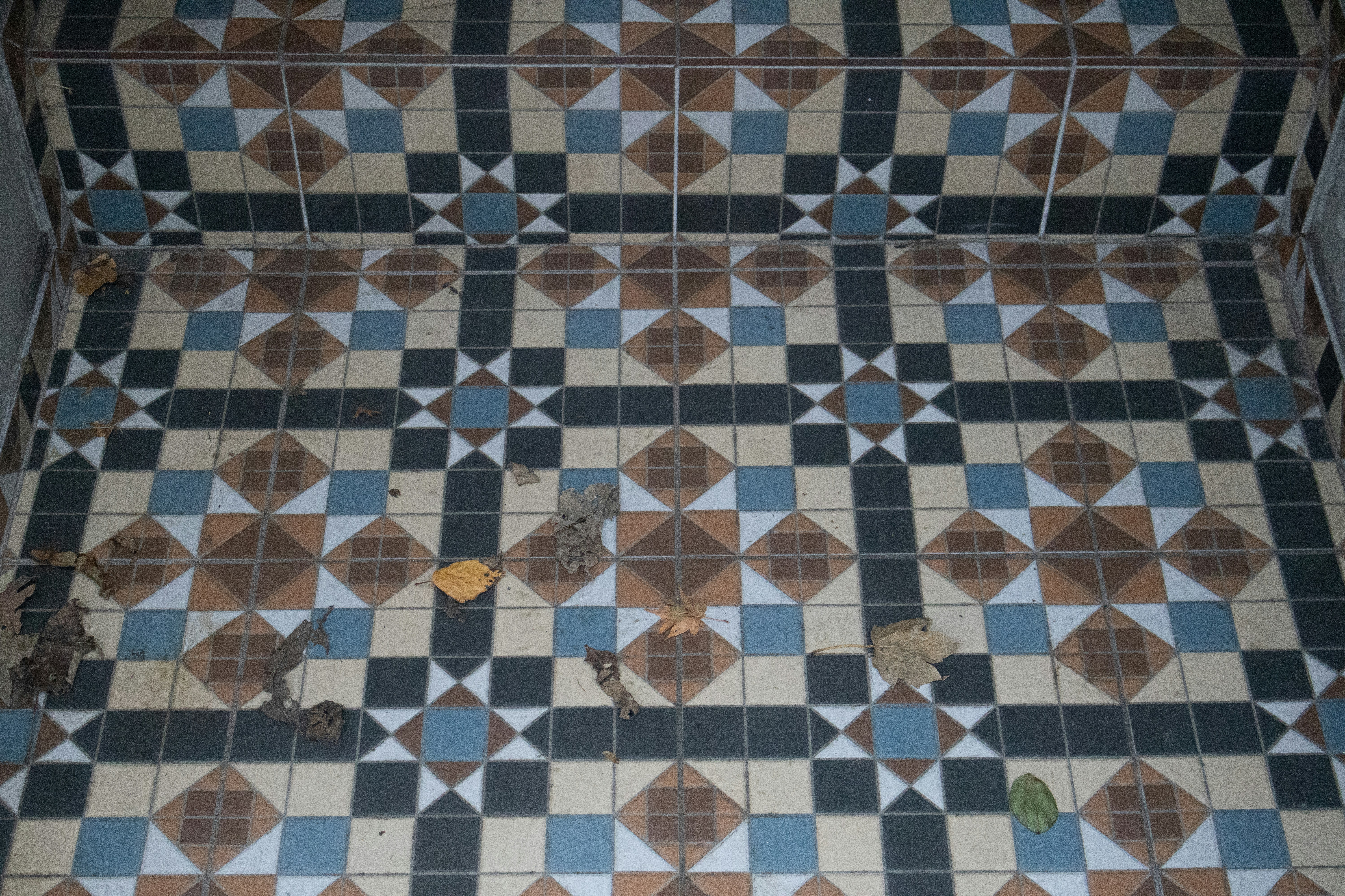 Geometric patterned floor tiles with debris