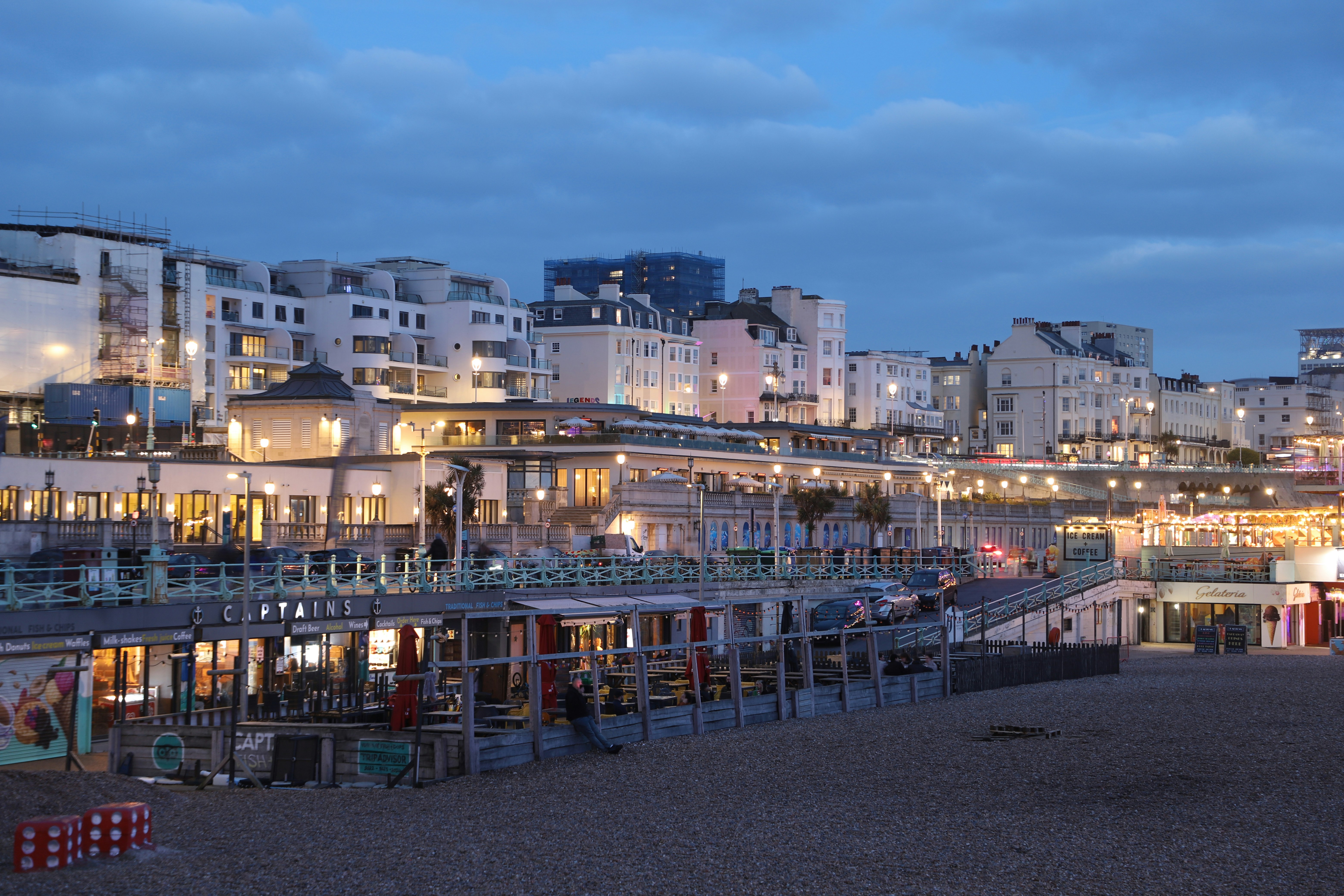 Buildings along the beach at dusk with lights on.