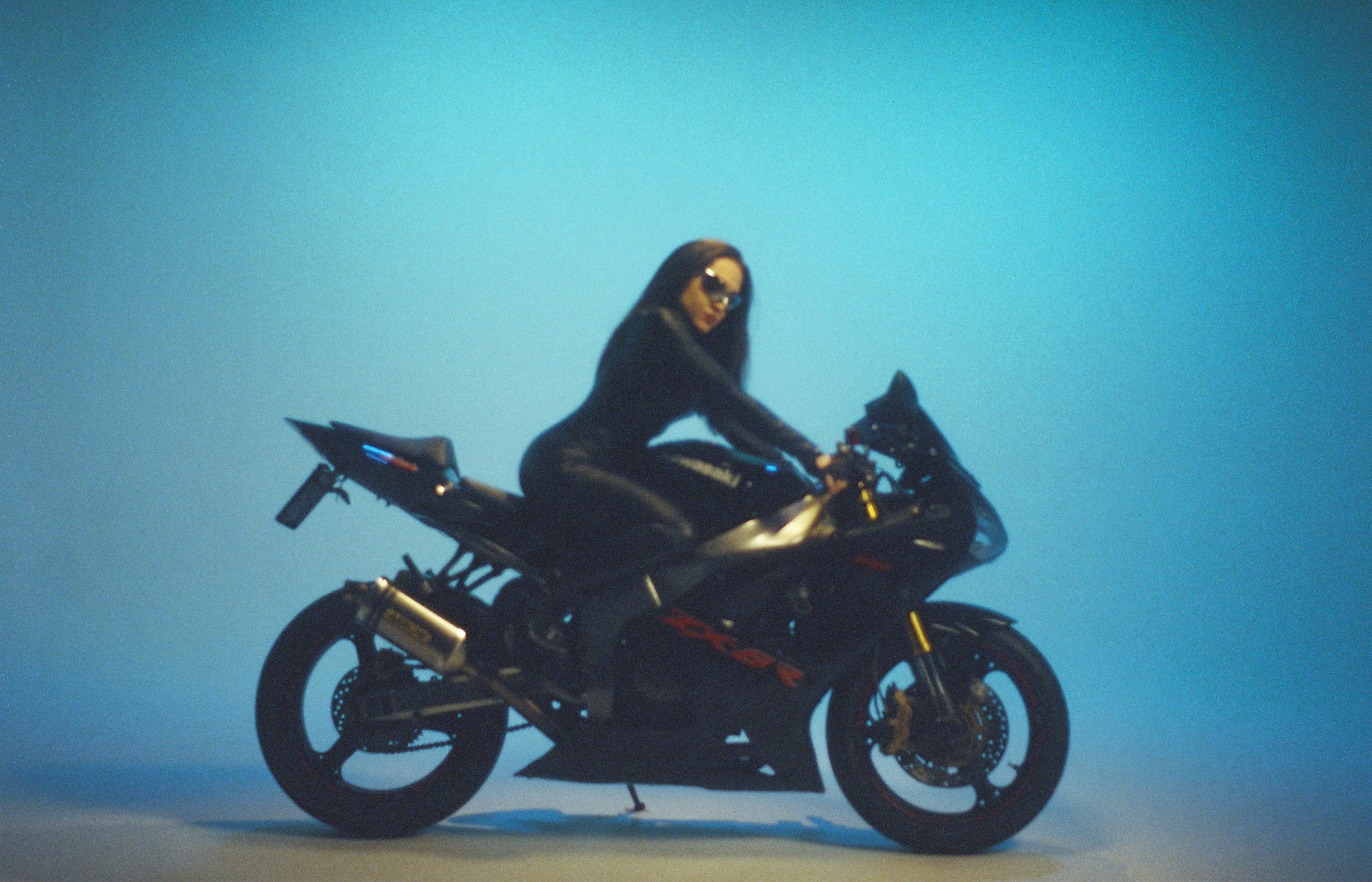 Woman in black riding a motorcycle