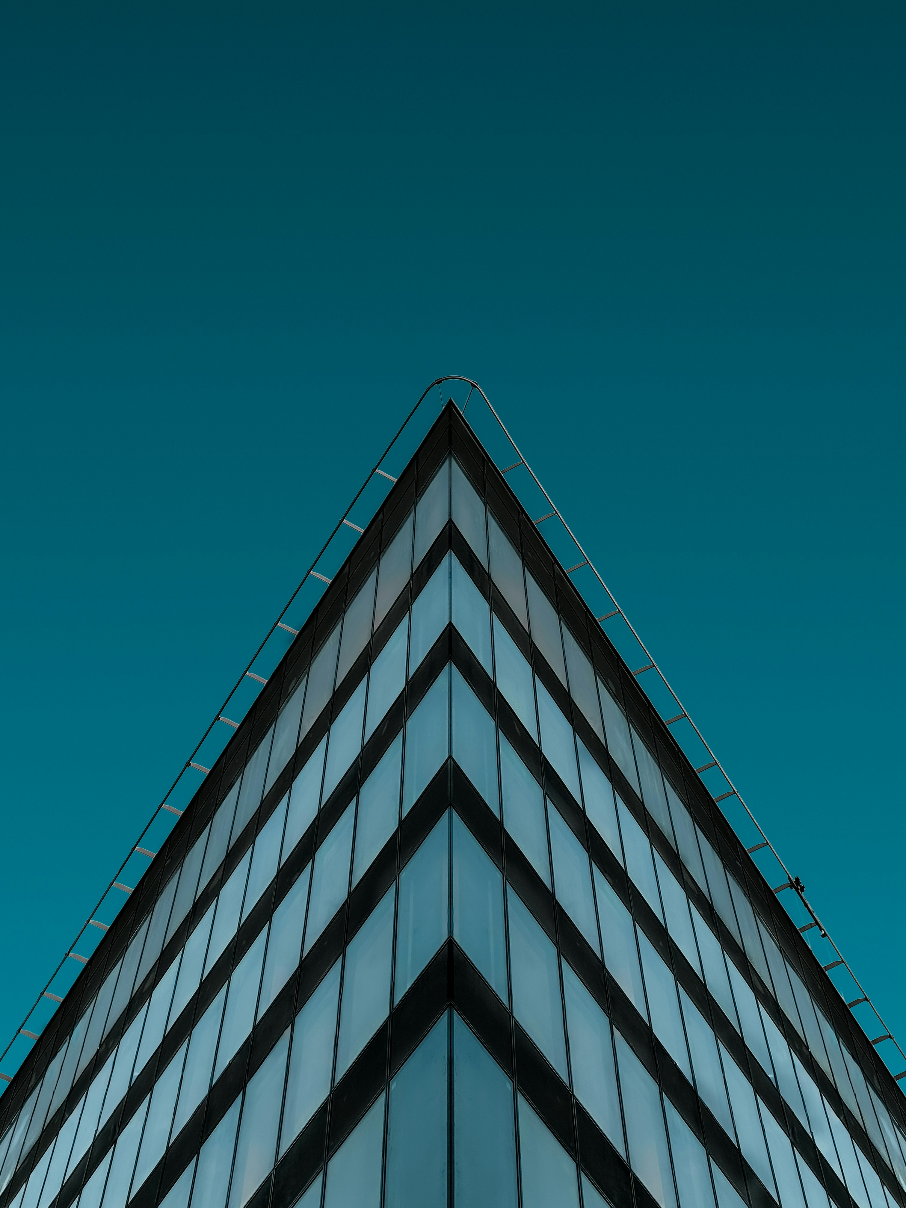 Modern glass building corner against clear blue sky