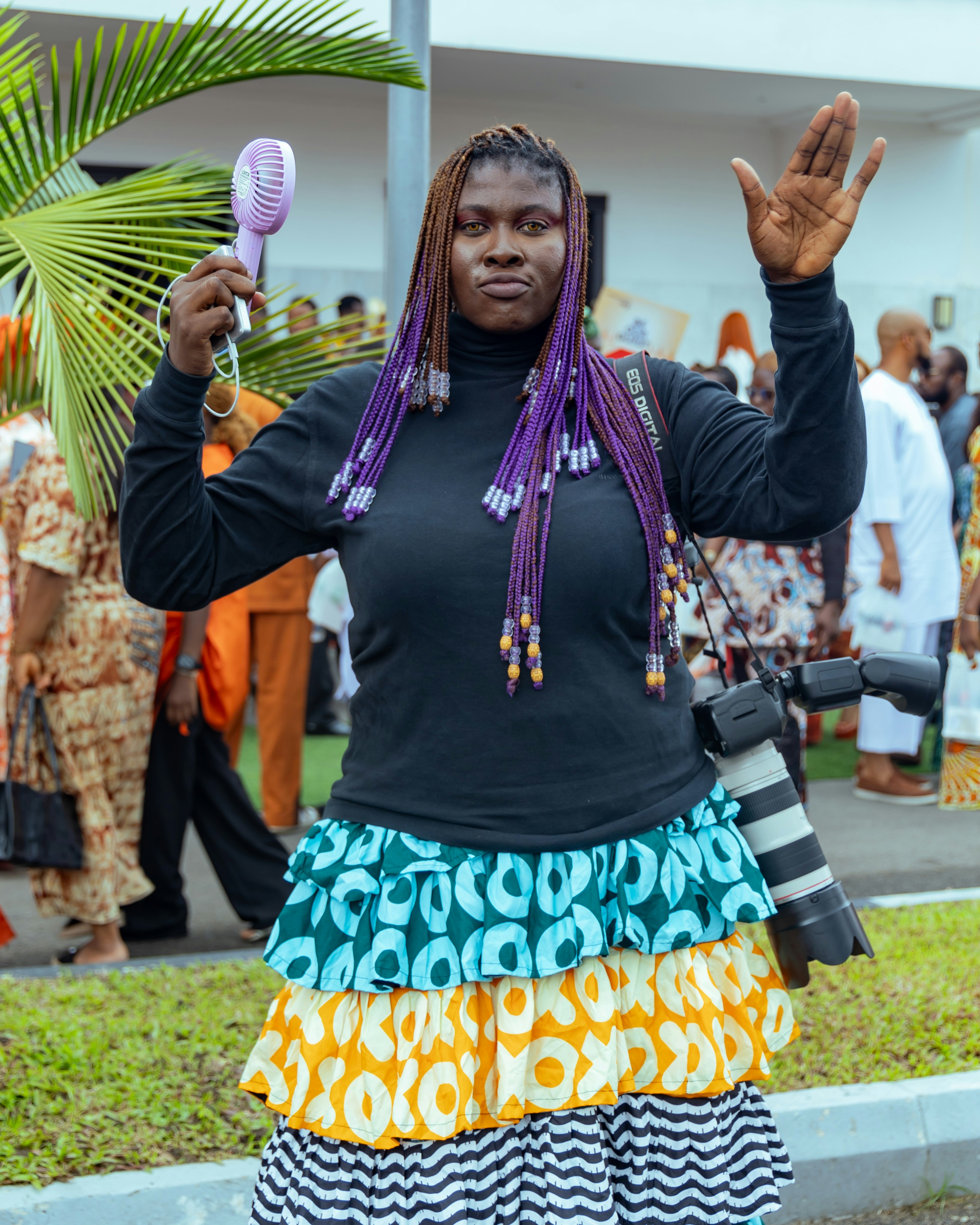 Woman with purple braids holds a microphone and camera.