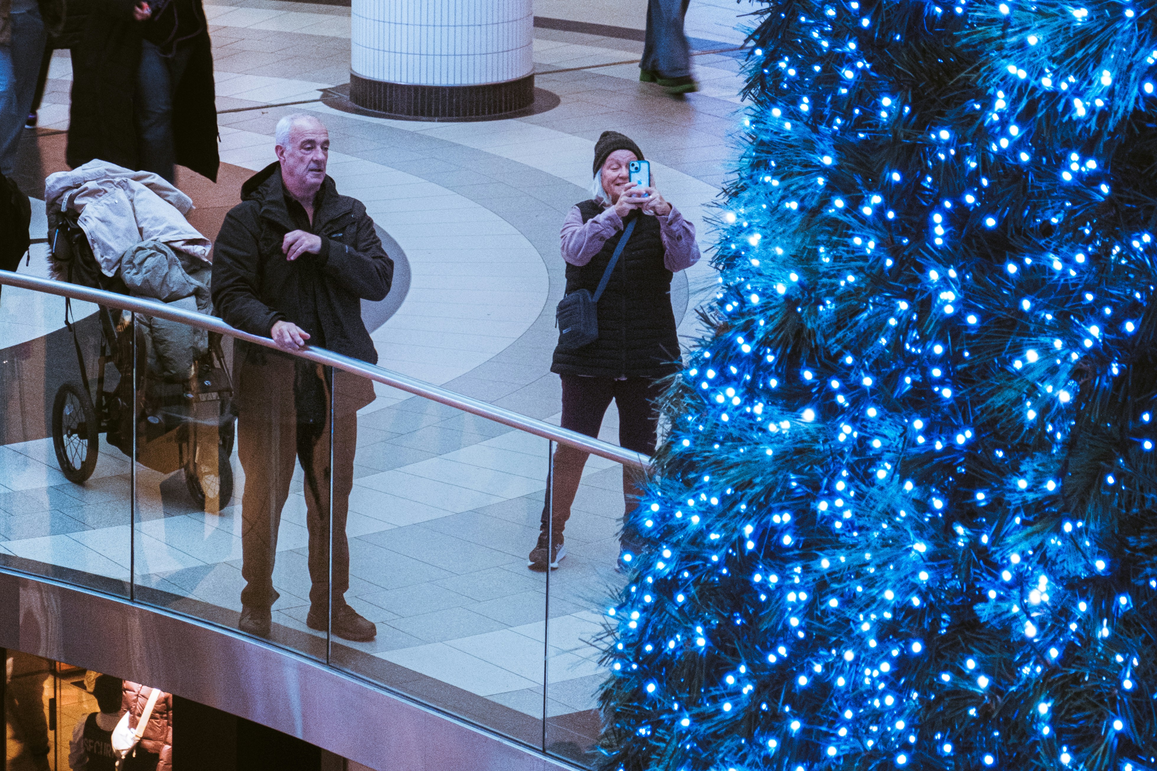 Shoppers looking at a large blue Christmas tree in a mall