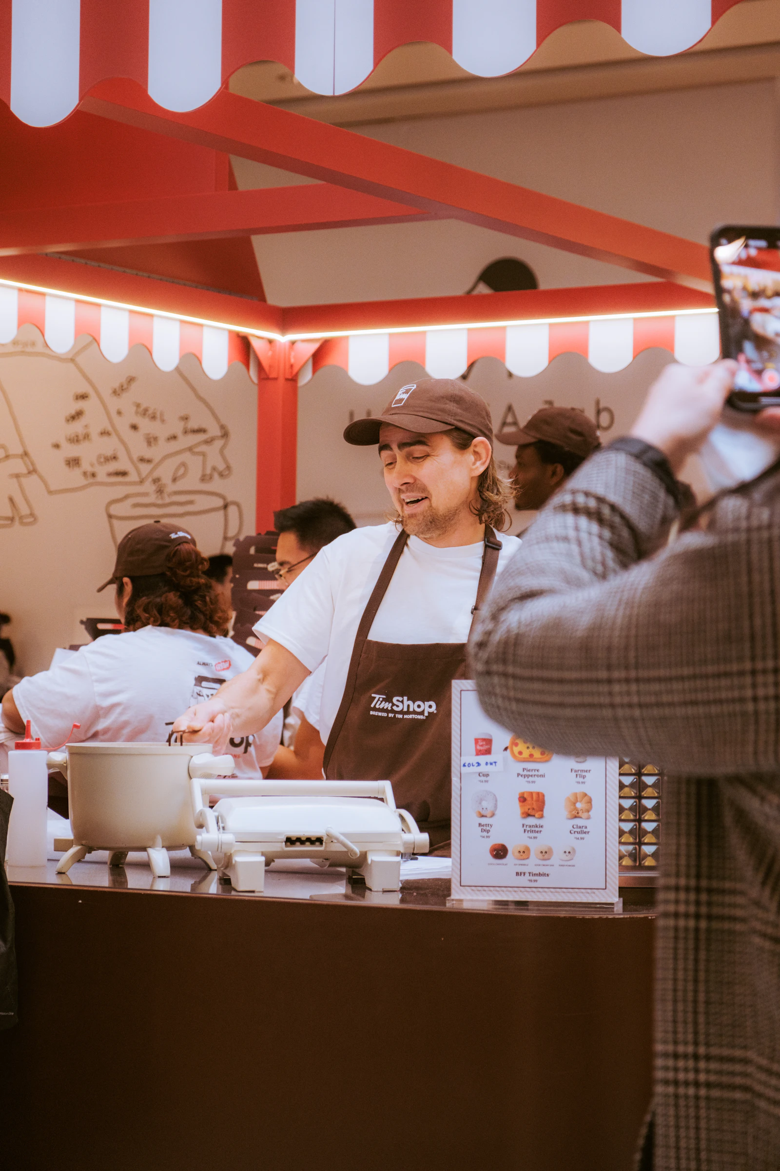 A person in an apron working at a food stand, handing something across the counter to a customer