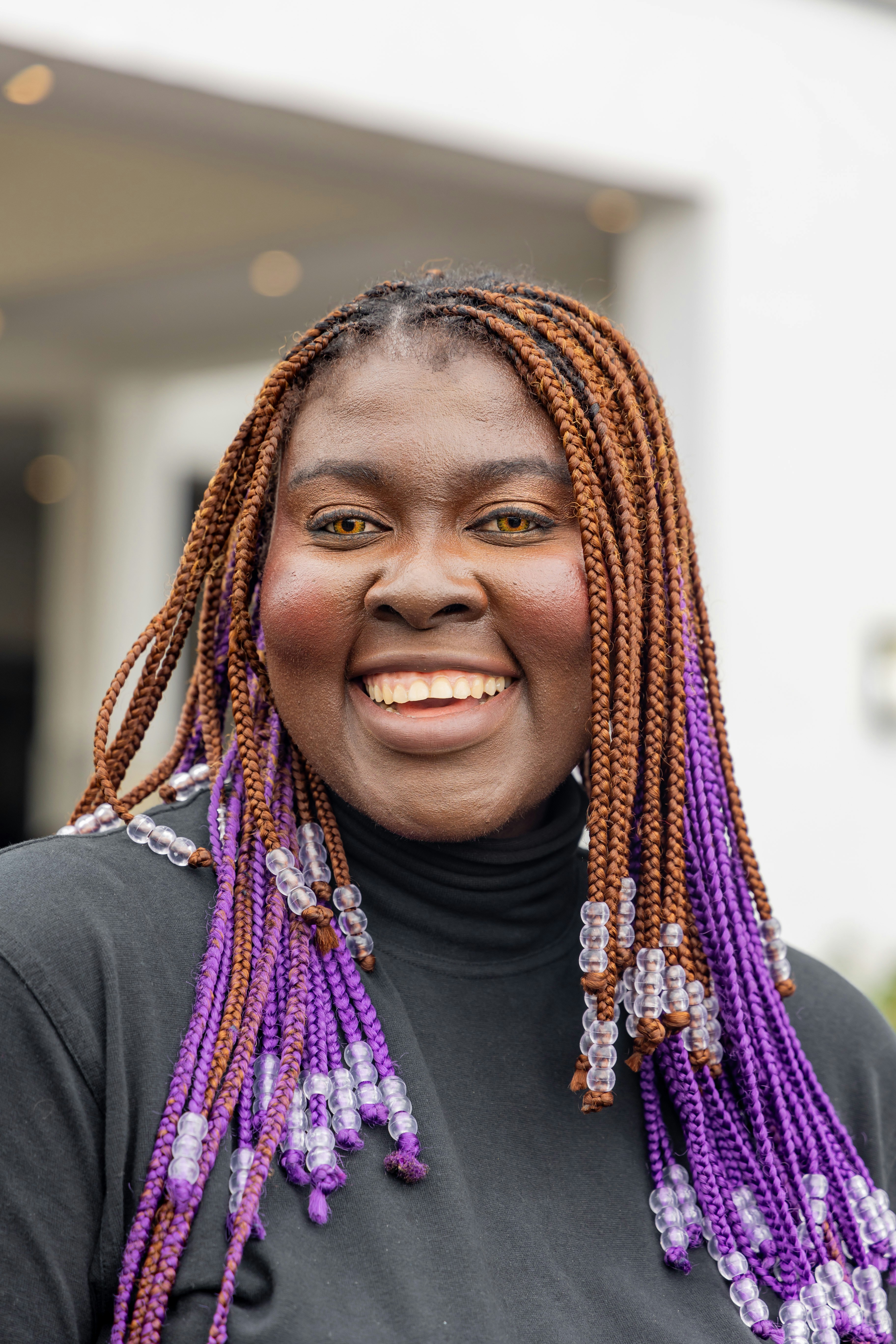Woman with braided hair and purple accents smiles
