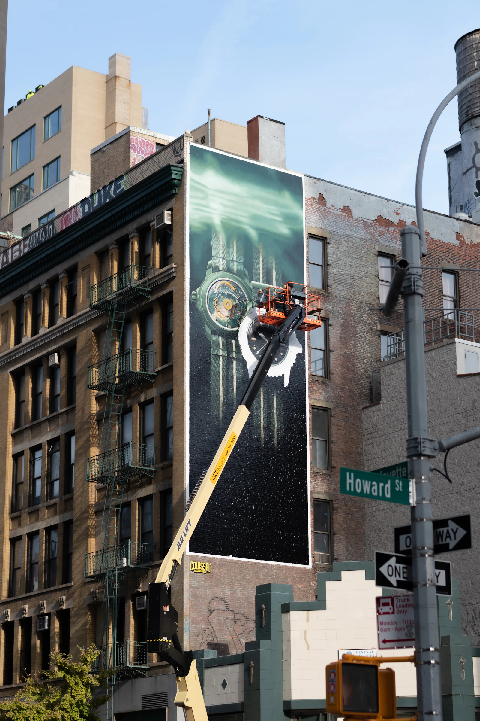 Crew installing a large printed wall wrap on a building facade