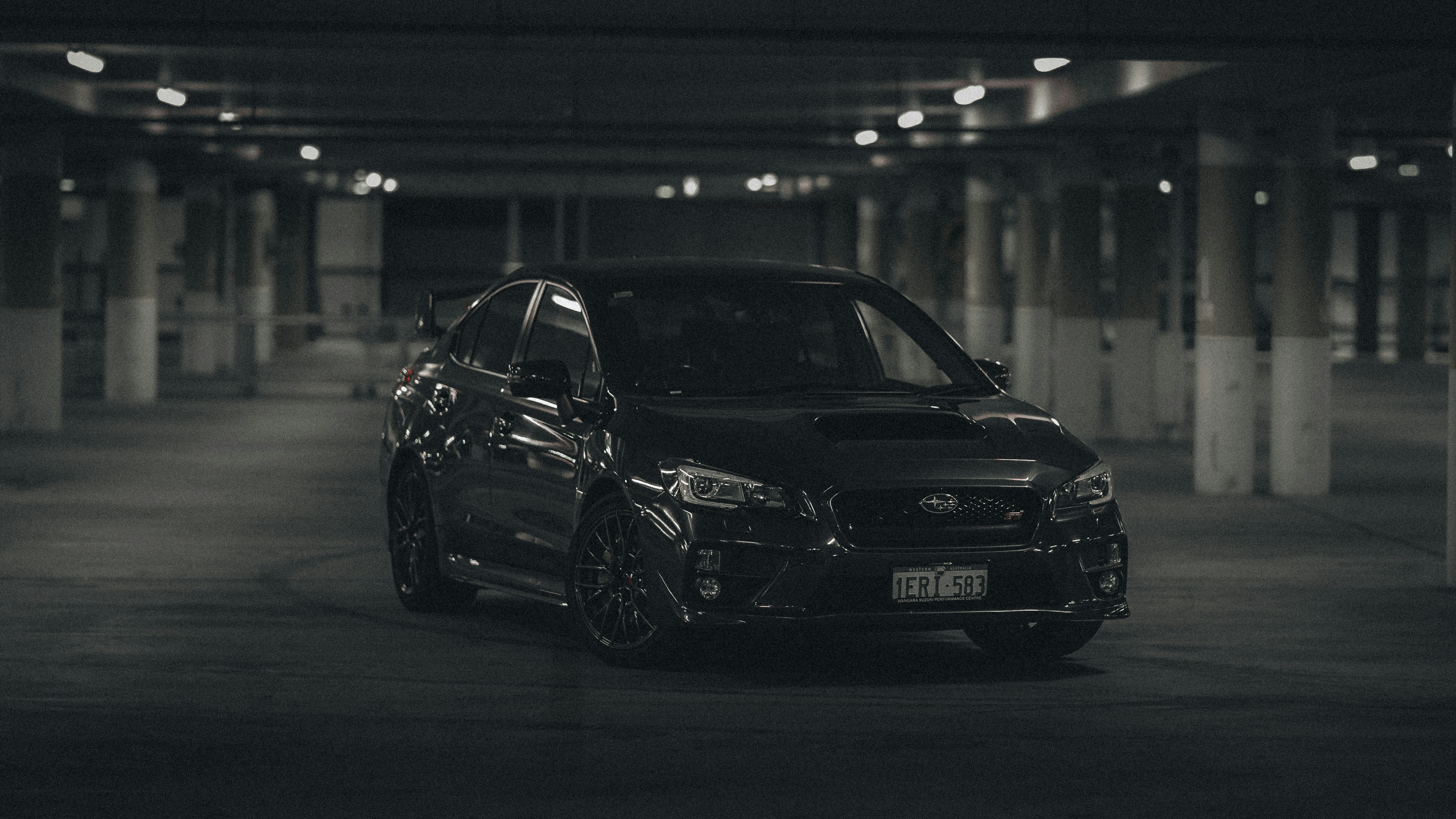 Black sports car parked in a dimly lit garage.