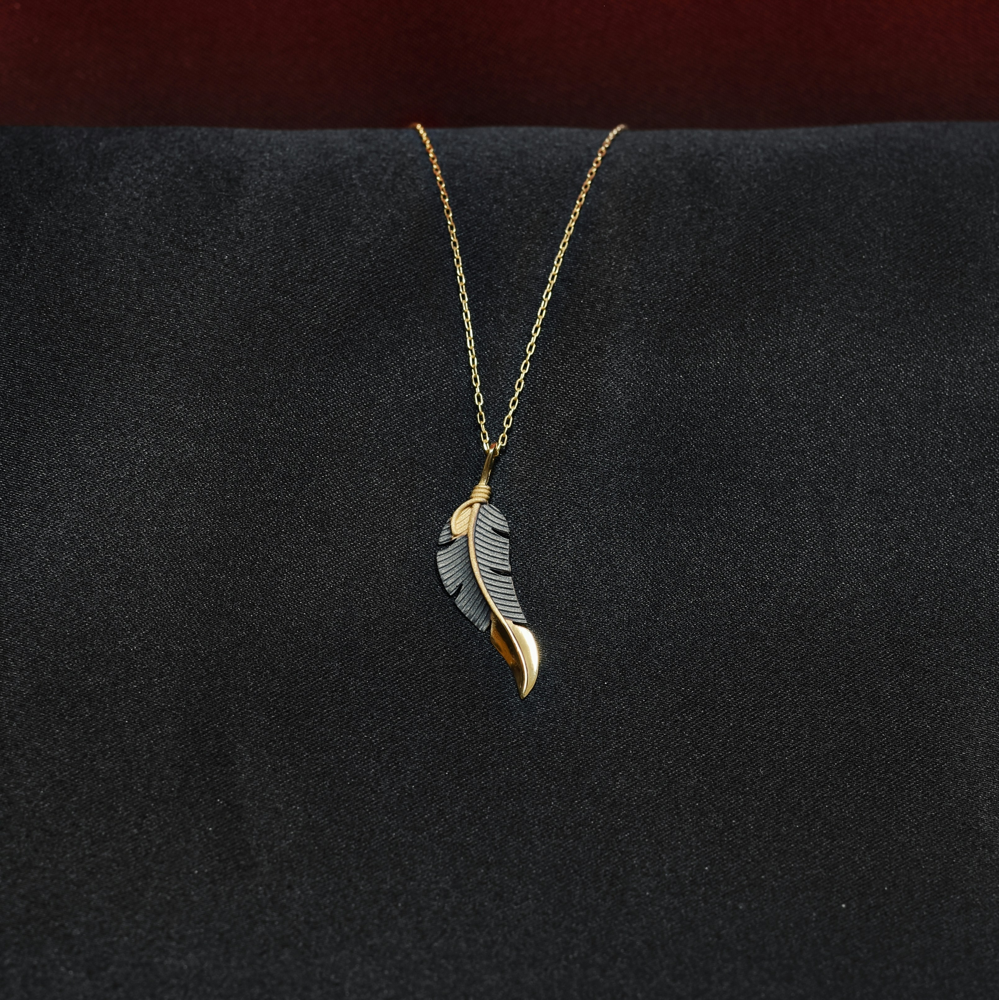 Gold necklace with a feather pendant.