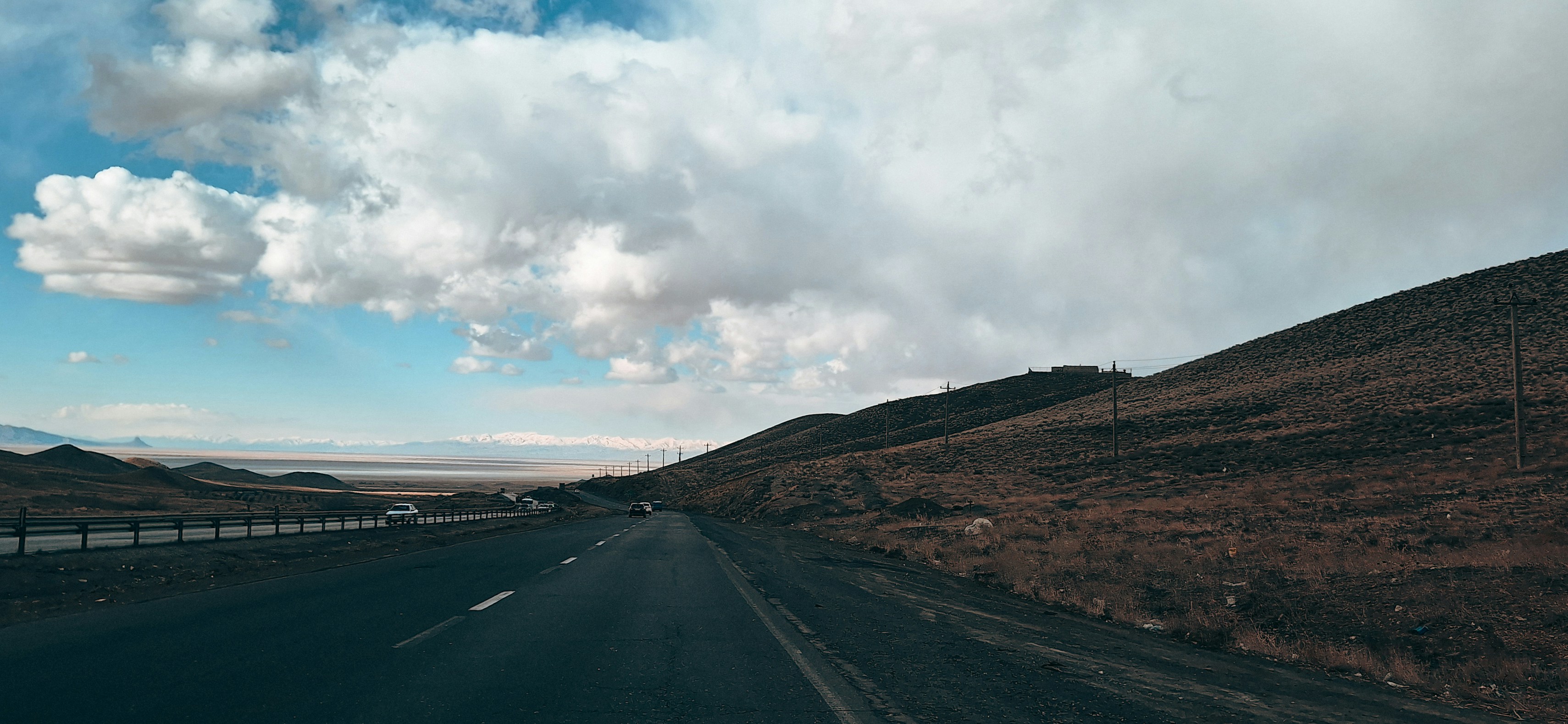 Driving on a road through a barren landscape under clouds.