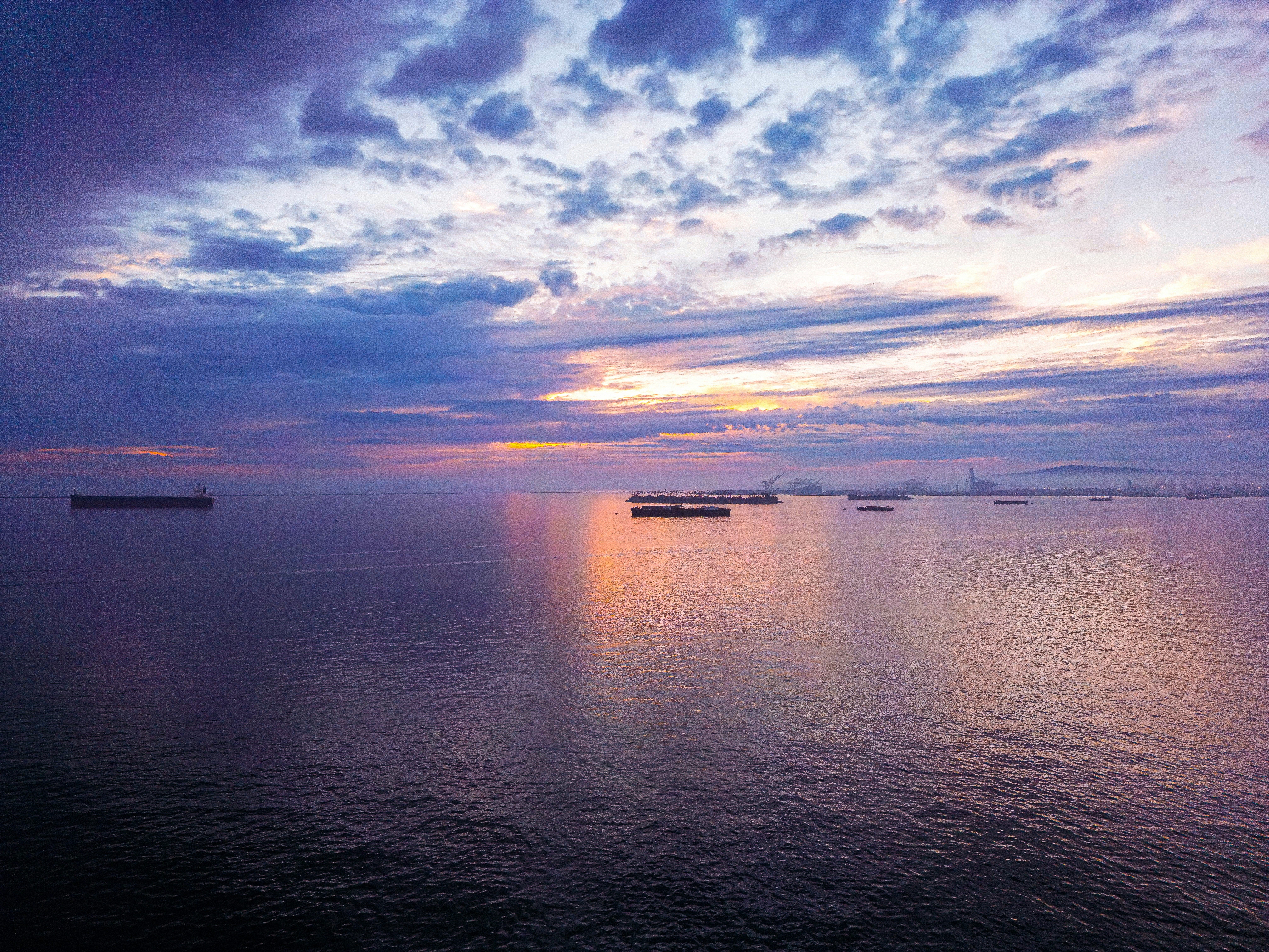 Ships on the ocean at sunset with dramatic clouds