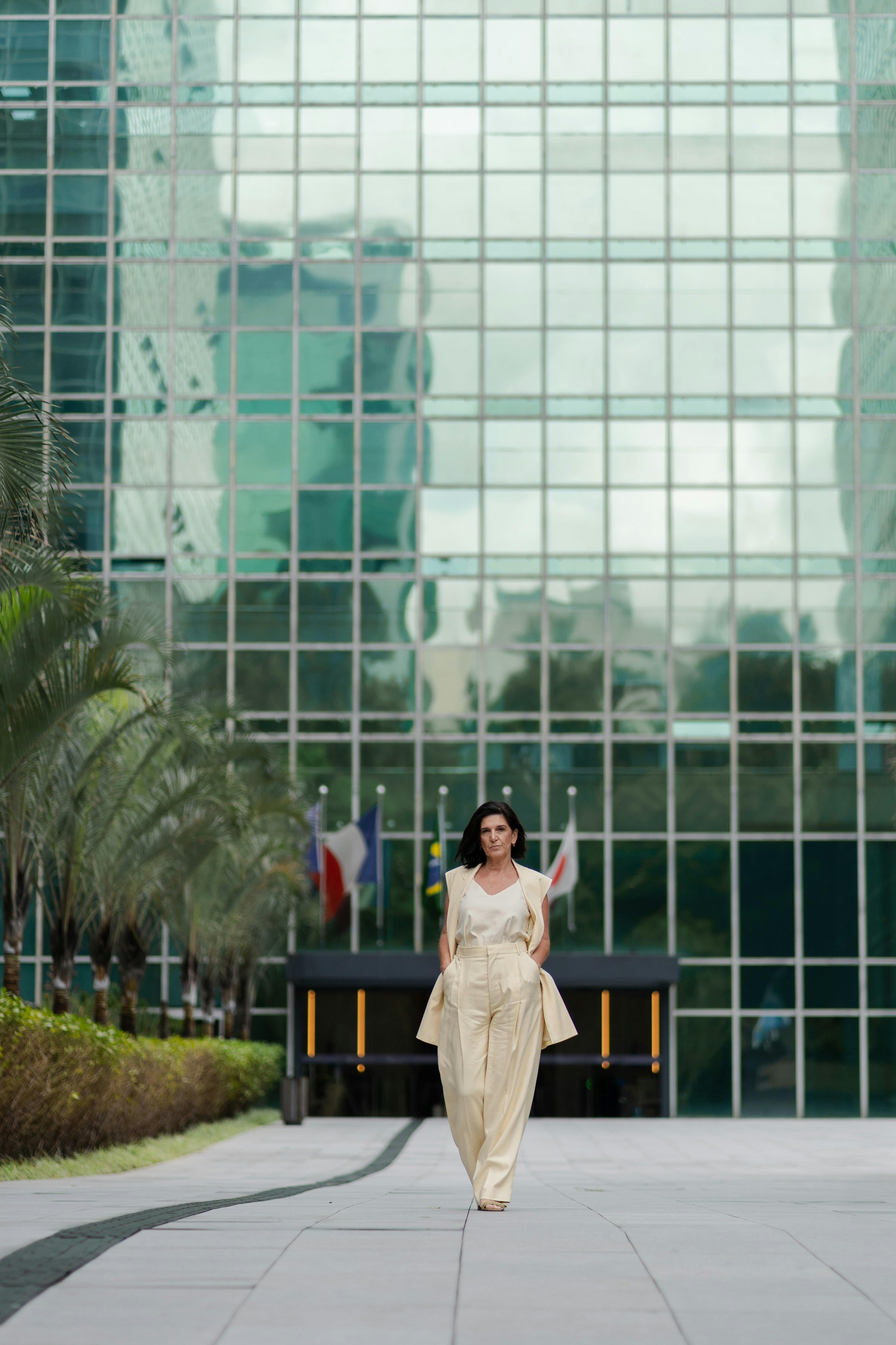 Woman in stylish outfit walking in front of modern building
