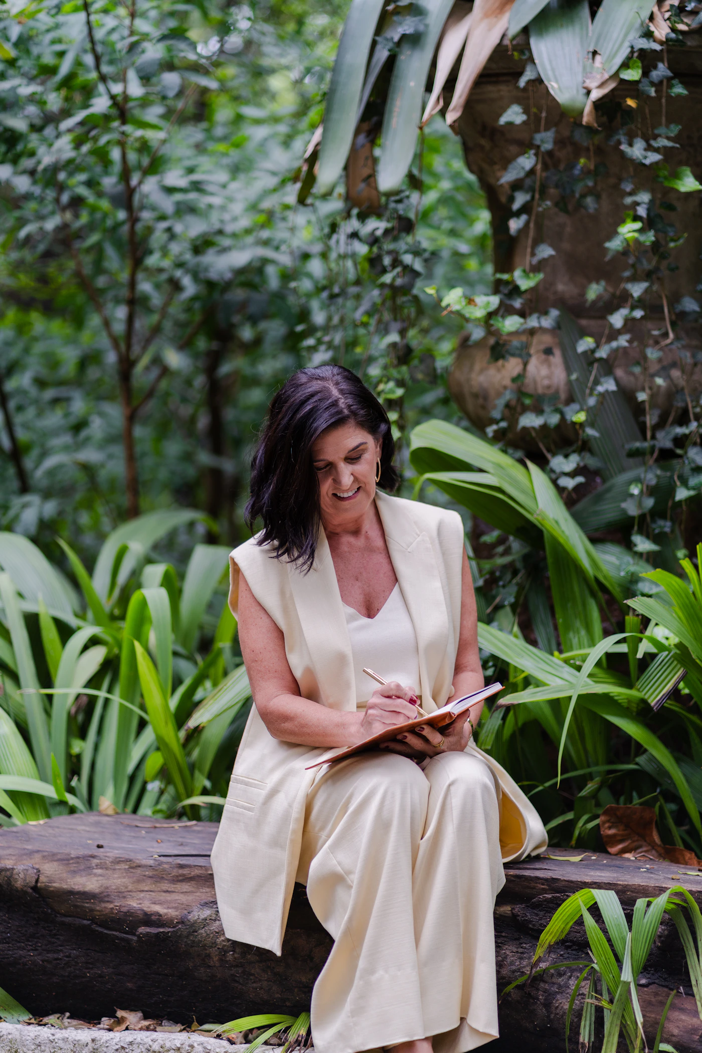 A person writing in a notebook surrounded by greenery