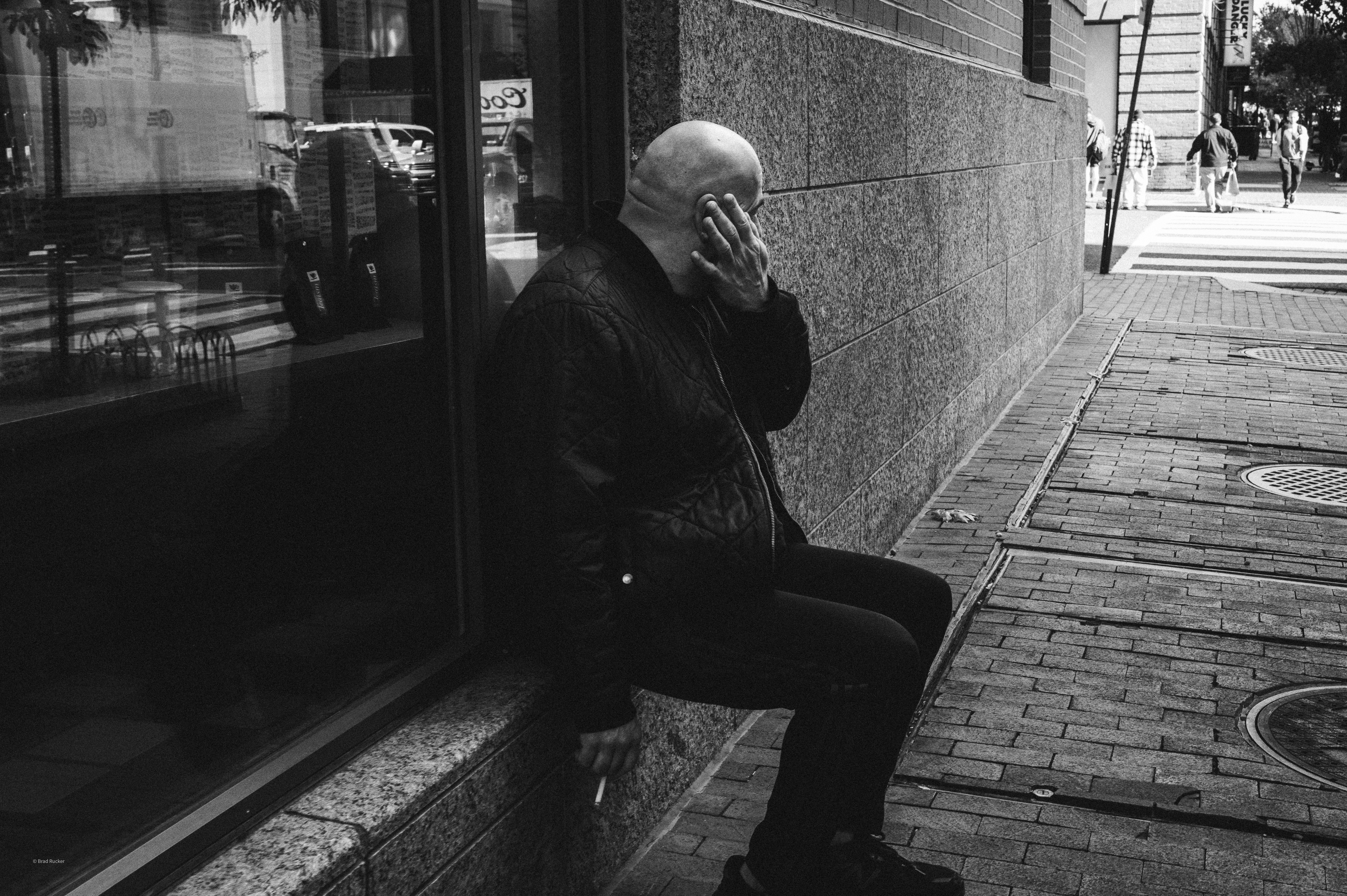 Man sitting on curb talking on phone