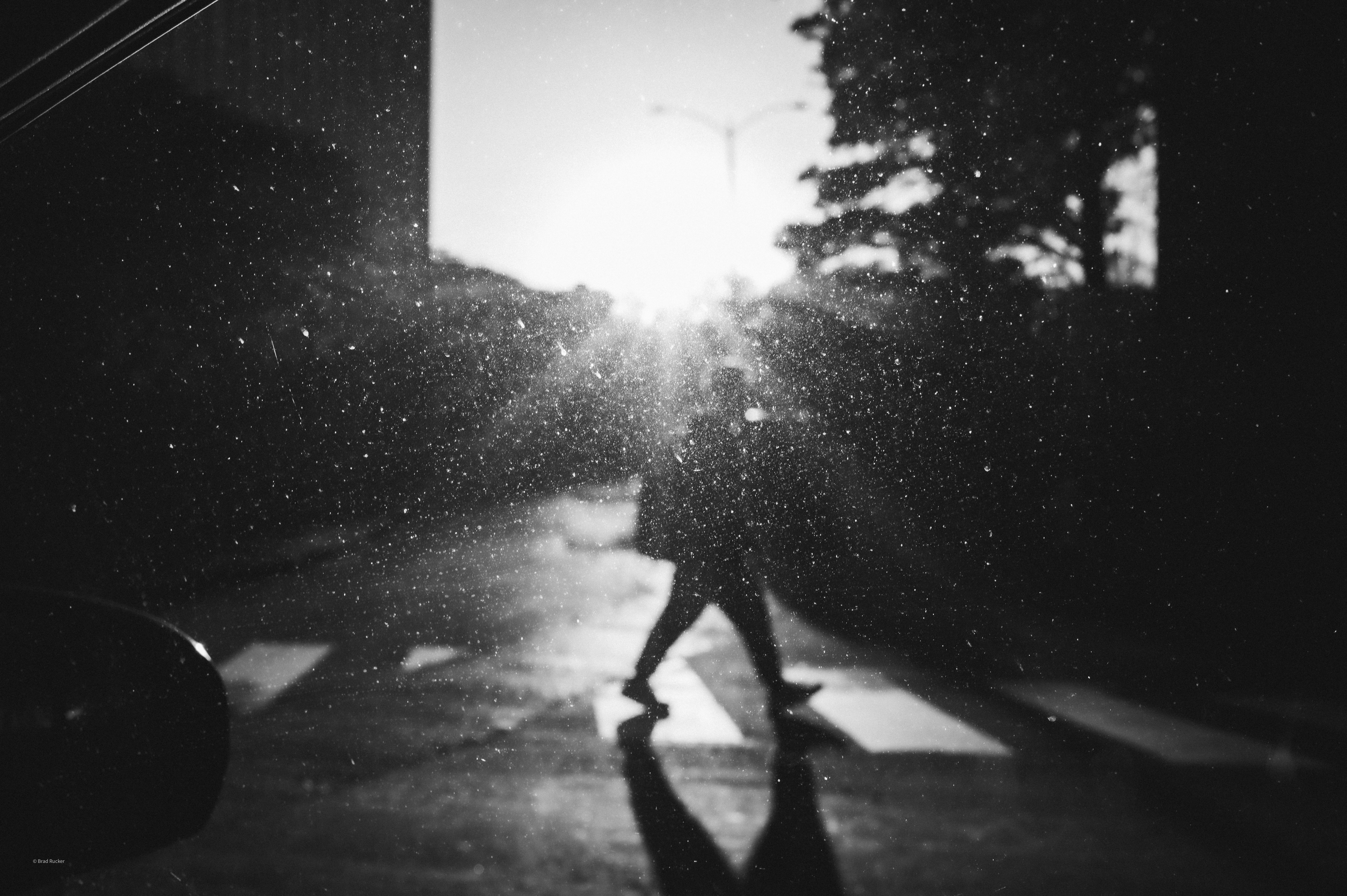 Person crossing street at sunset with sun flare
